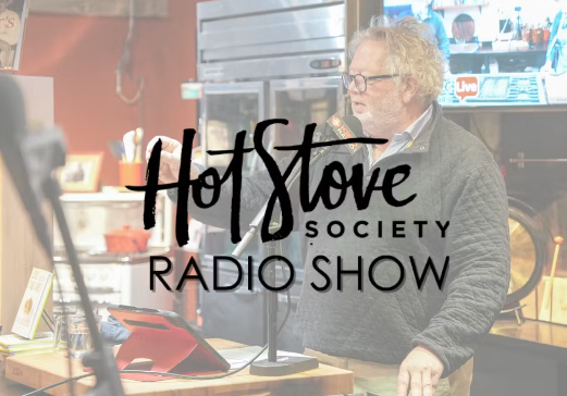 A man with gray hair and glasses speaking into a microphone during a radio show, with a logo overlay that reads 'Hot Stove Society Radio Show'.