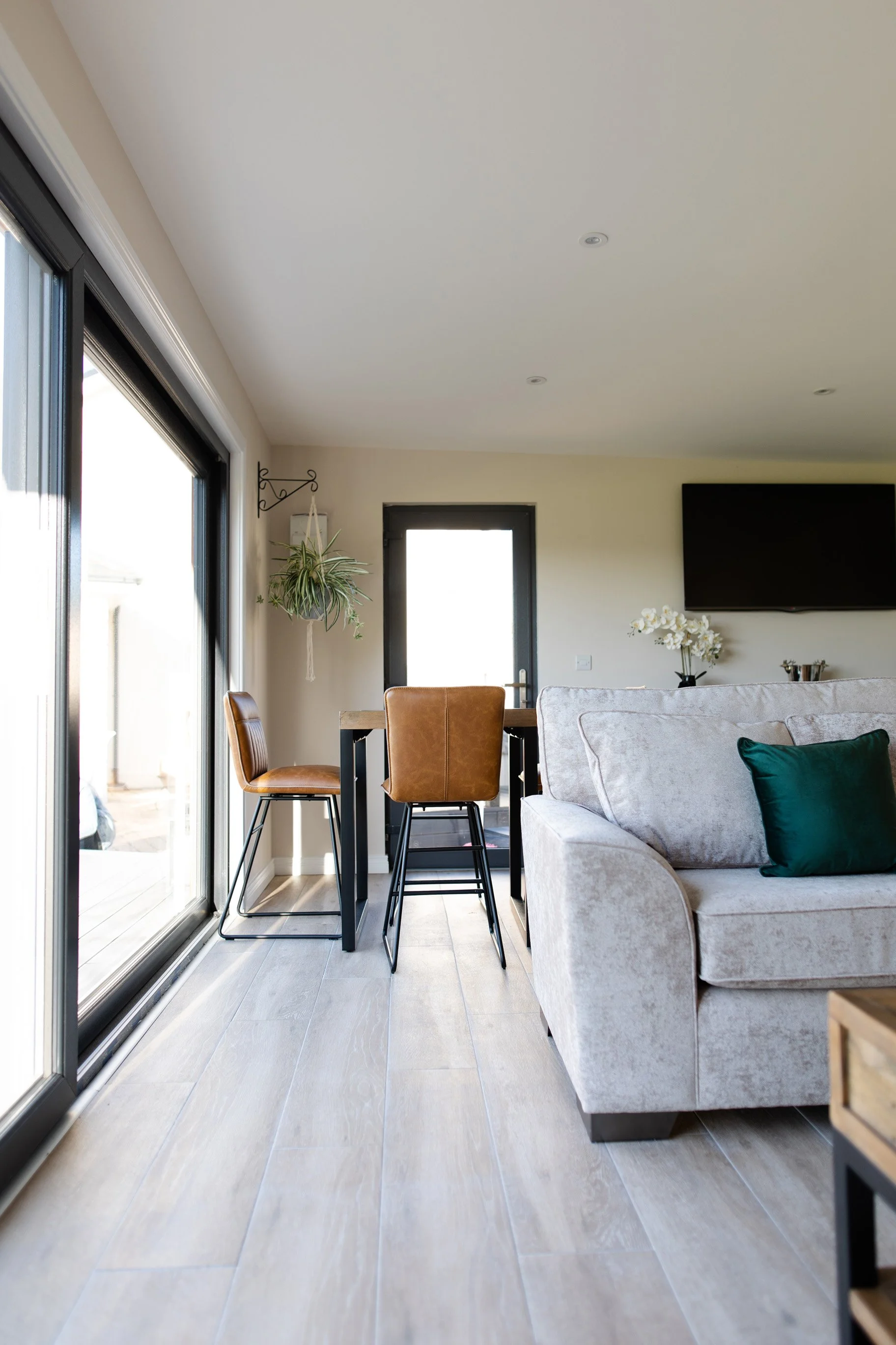 Modern living room with a sliding glass door, dining table, sofa, and wall-mounted TV