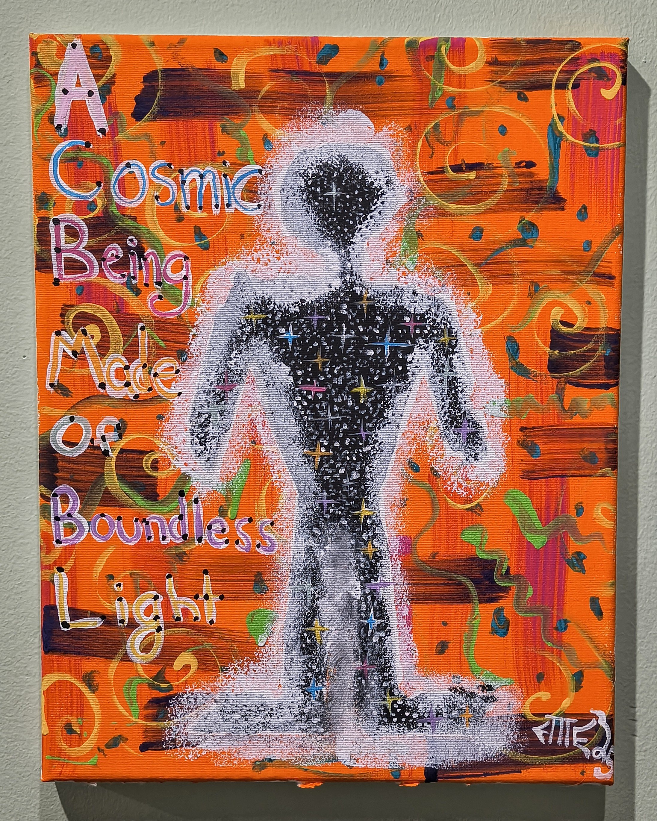 Colorful abstract painting with a humanoid figure made of black and white splatters and stars, surrounded by orange and multicolored swirling patterns. The text on the painting reads 'Cosmic Being Made of Boundless Light'.
