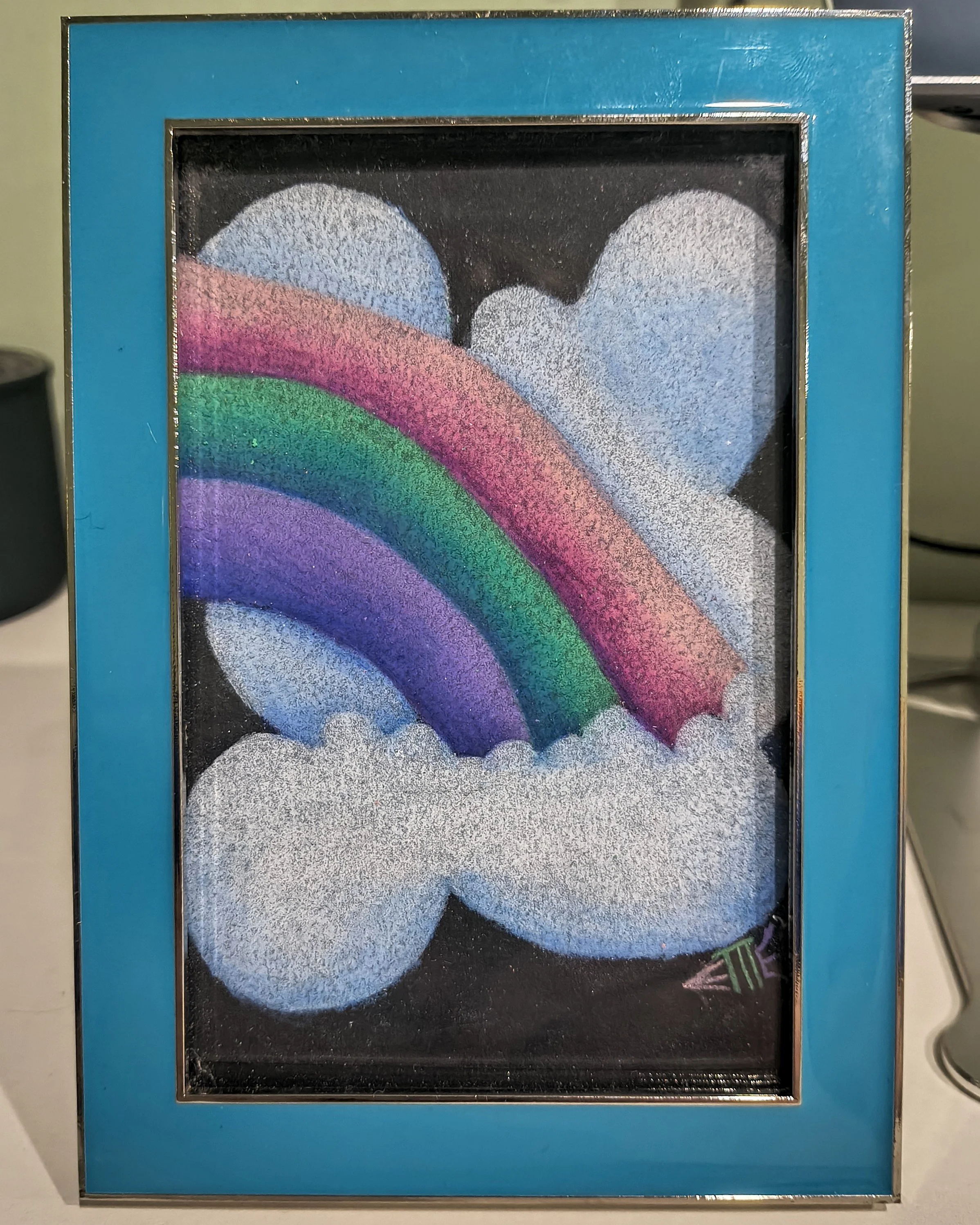 Colorful drawing of a rainbow with four bands in pink, green, blue, and purple, surrounded by white clouds and two pastel blue hearts on a black background, framed in a teal frame.