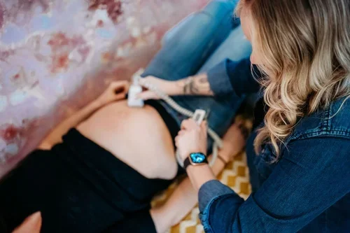 A woman undergoing an ultrasound scan on her pregnant belly in a medical setting.