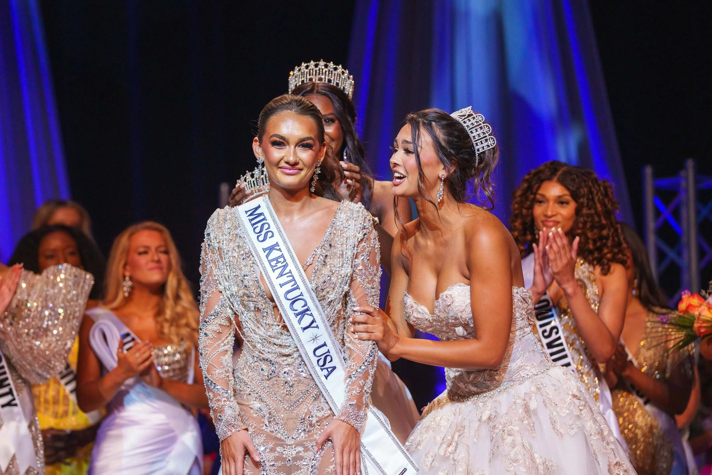 Beauty pageant winners wearing crowns and sashes on stage, celebrating their victory.