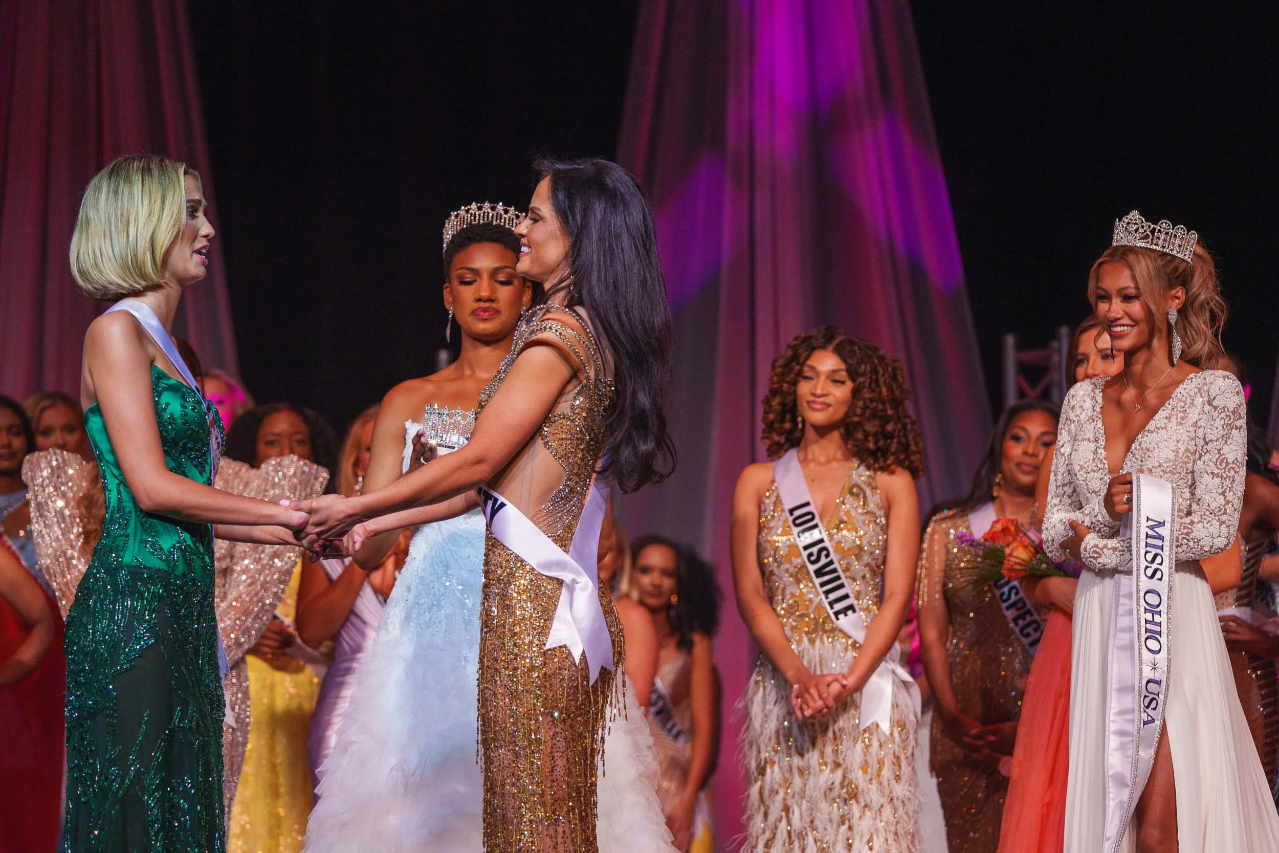 Miss Ohio contestants on stage, wearing elegant gowns and tiaras, with sashes and flowers, during the beauty contest awards ceremony.