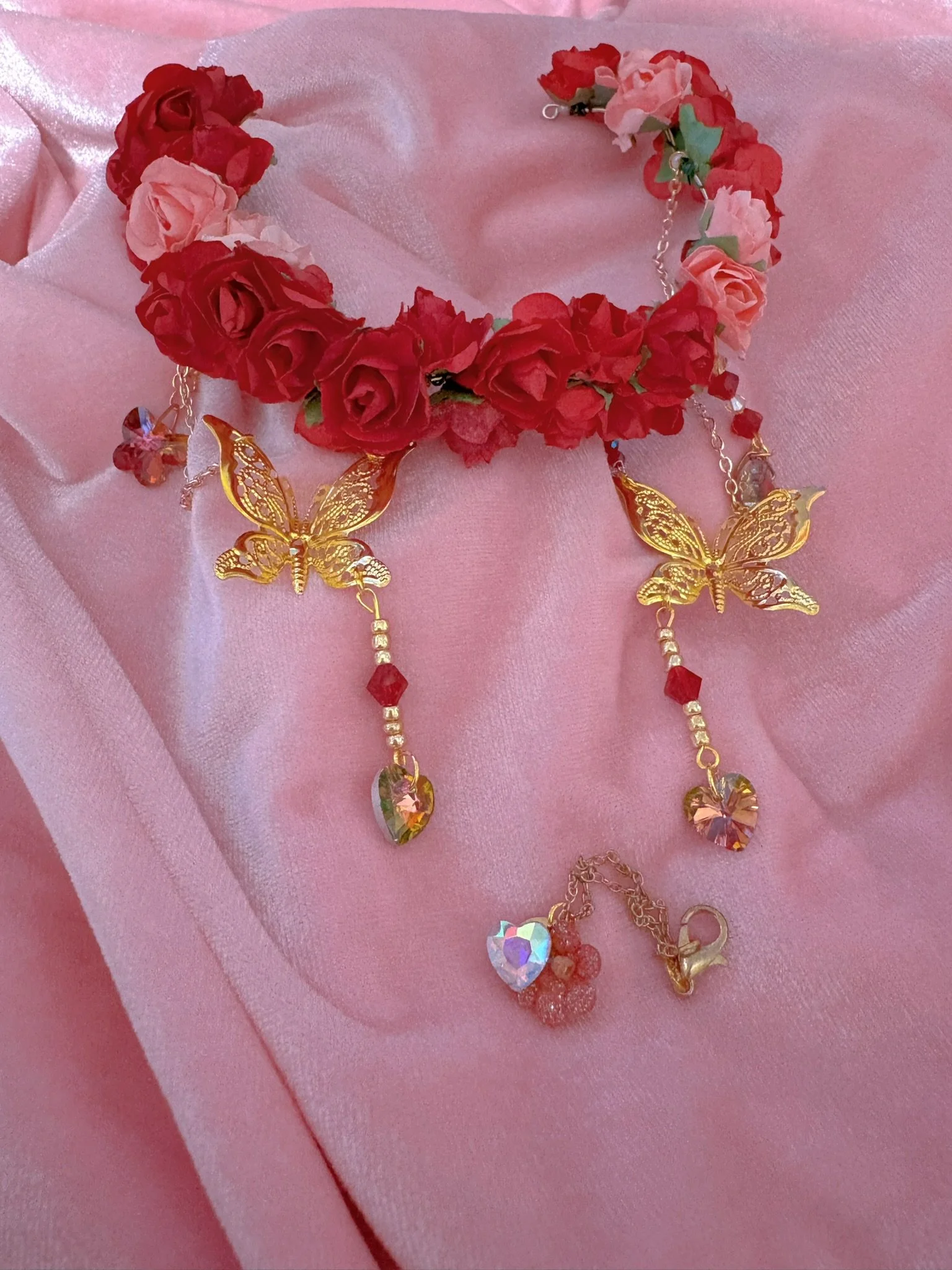 $40.00. 

Red rose and coral pink rose crown with dangling butterfly and crystal heart details. Includes matching crystal and flower necklace. 

Adjustable, best fits size 7/8 through size 9/10 heads.