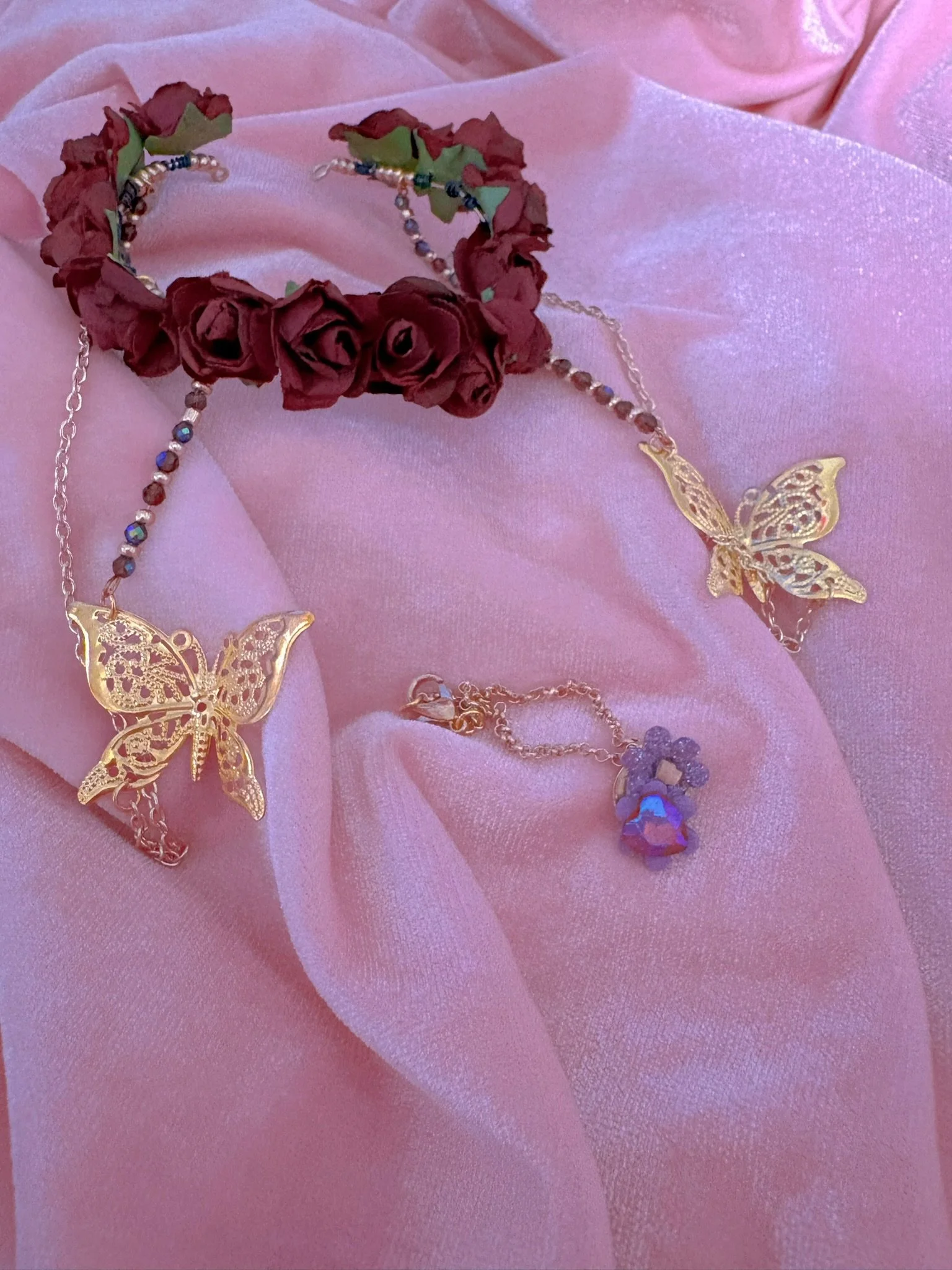 $30.00. 

Dark red rose crown with dangling gold butterflies and long gold chains. Includes matching crystal and flower necklace. 

Adjustable, best fits size 6/7 through size 9/10 heads.