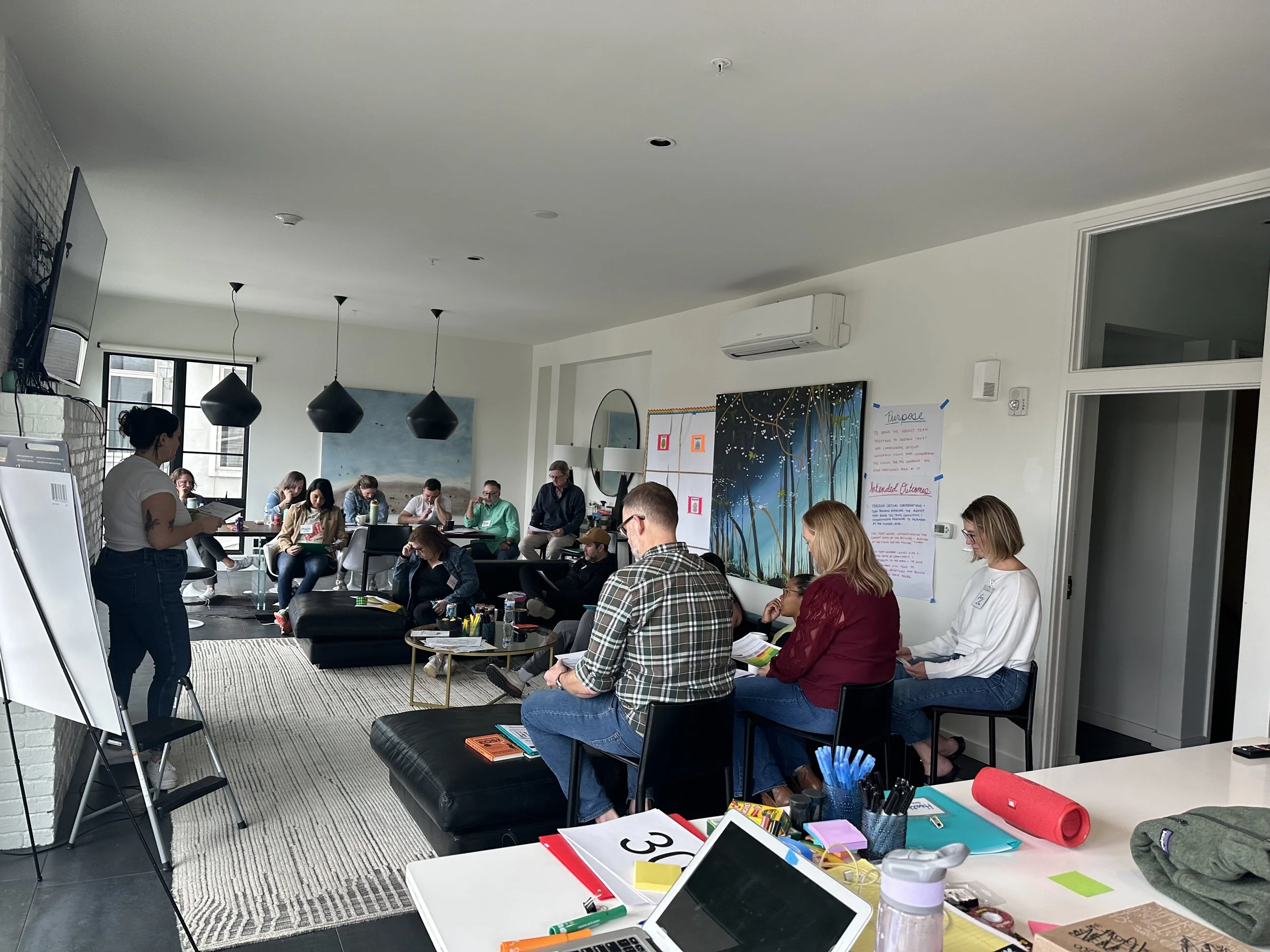 Kinship coach, Jules, facilitates an in-person session with a group of about 15 people in a living room in Nashville, TN.