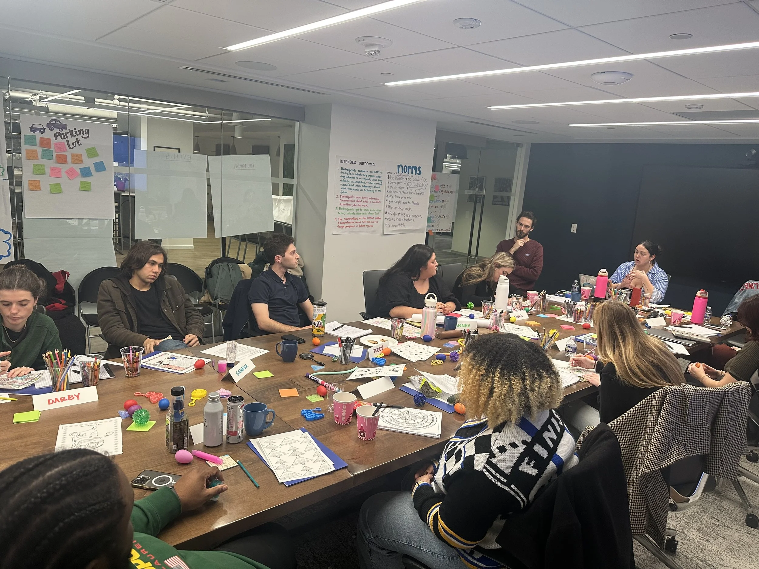 Kinship coaches facilitate a group debrief at a conference table at a retreat in Washington, DC.