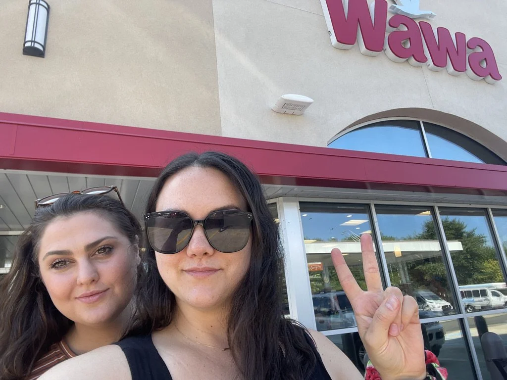 Kinship founders and coaches, Jules and Sara, pose outside of a Wawa on a work trip to Pennsylvania.