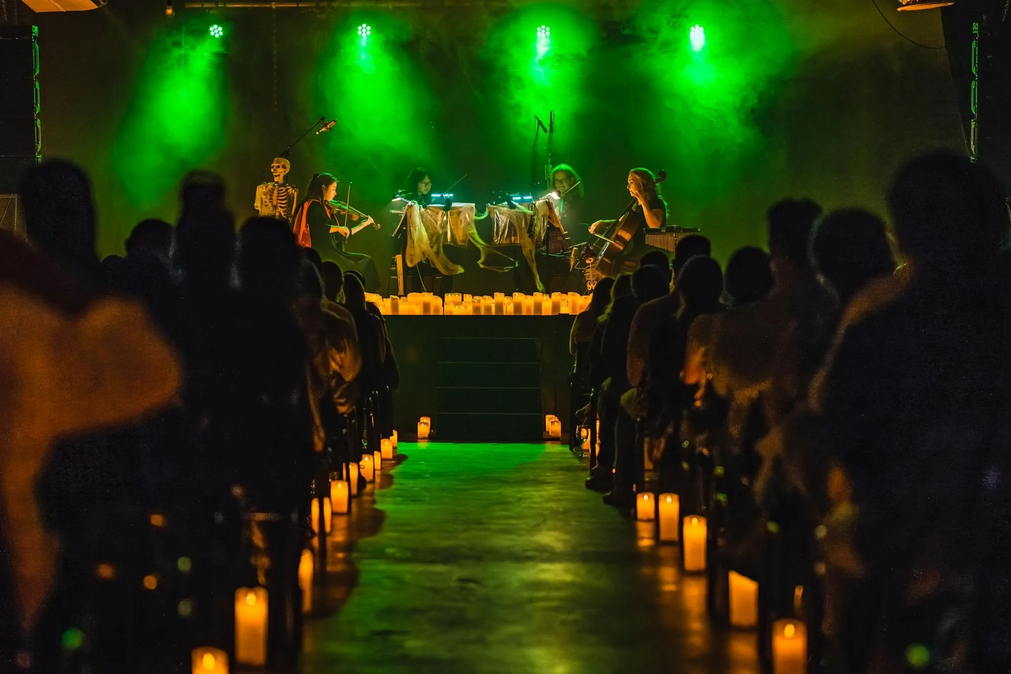 Photo of Paradiso Strings playing in concert surrounded by candlelight and Halloween decorations