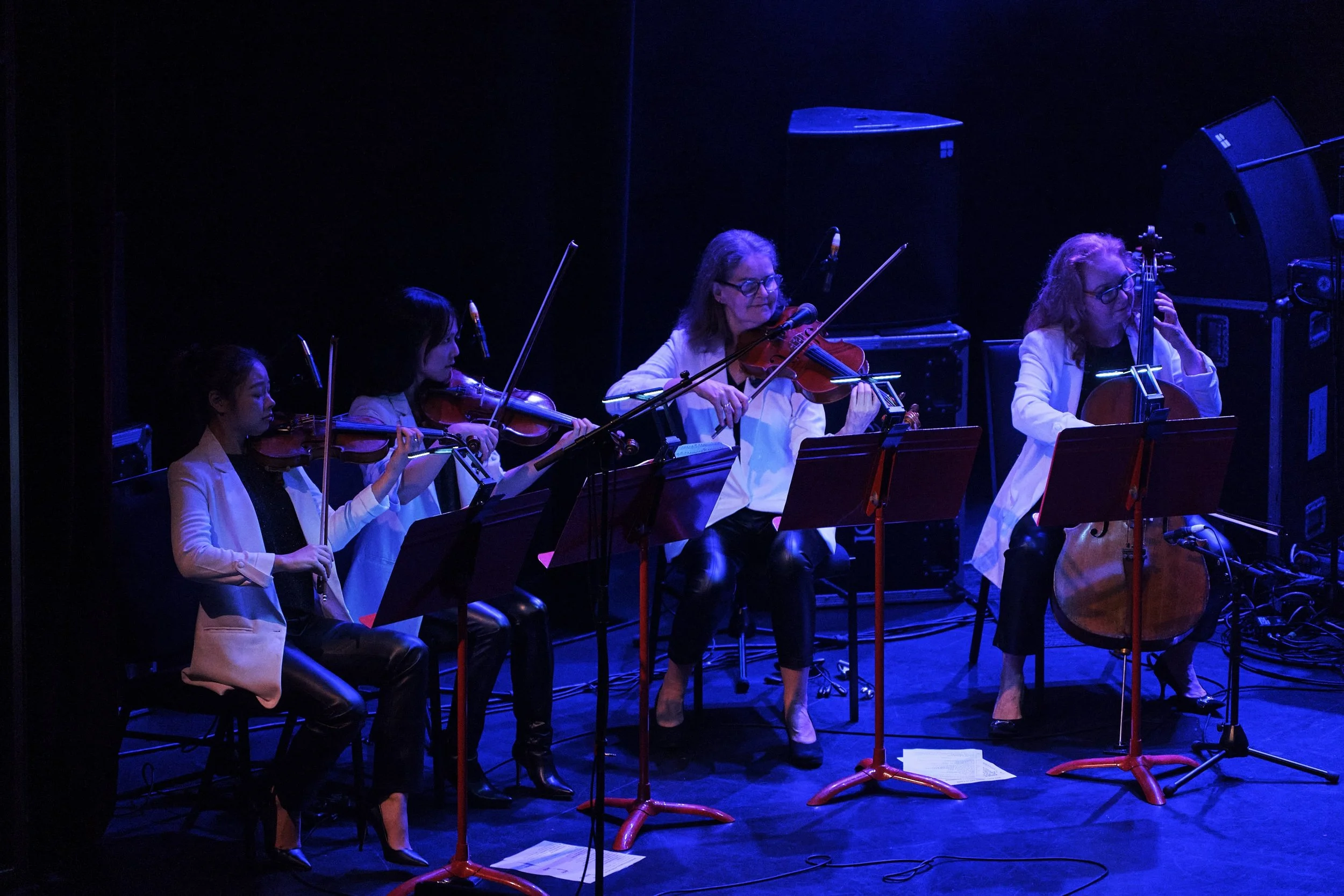 low light shot of Paradiso Strings on stage bathed in blue light