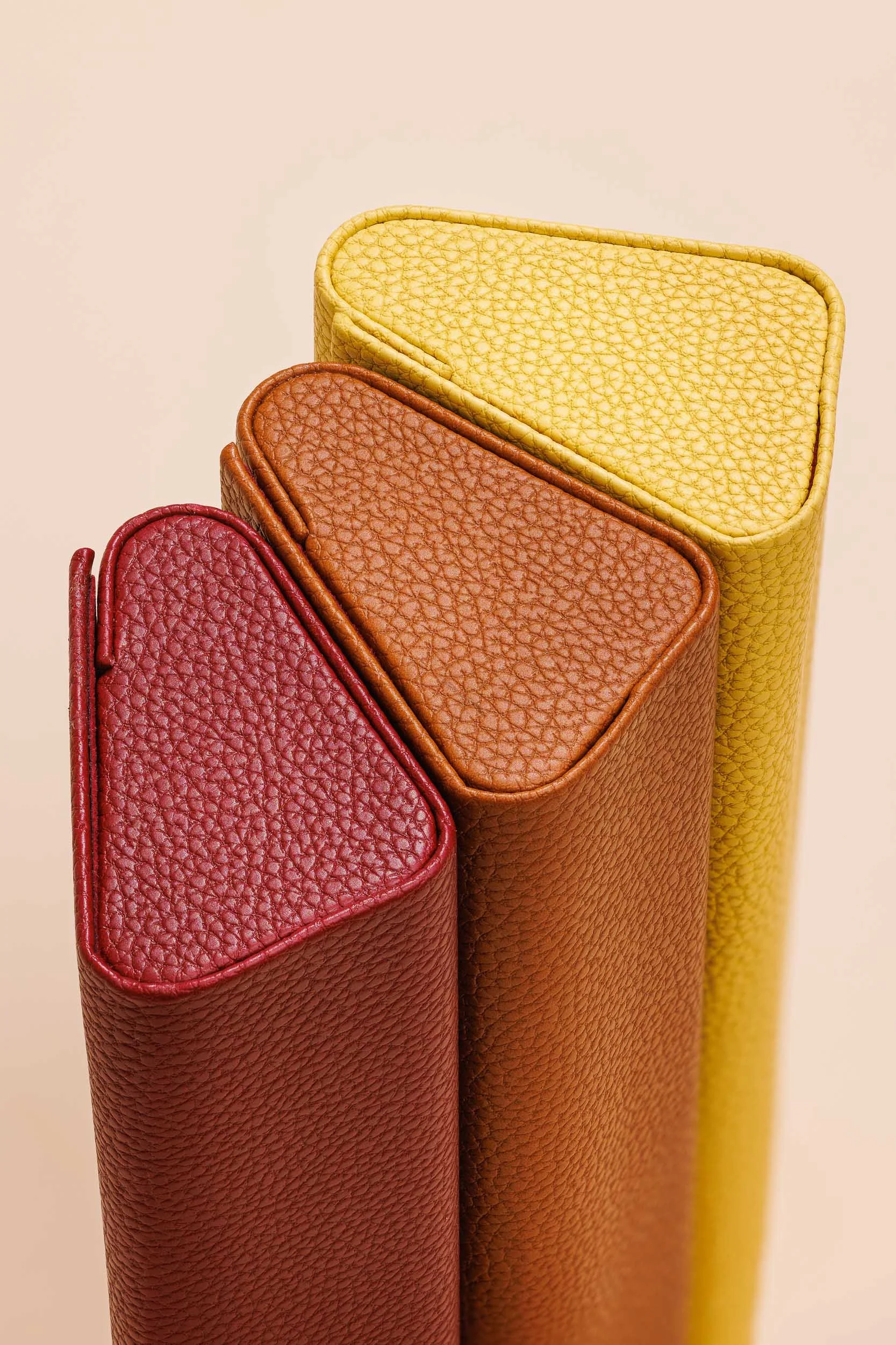 Stacked leather wallets in red, brown, and yellow colors.
