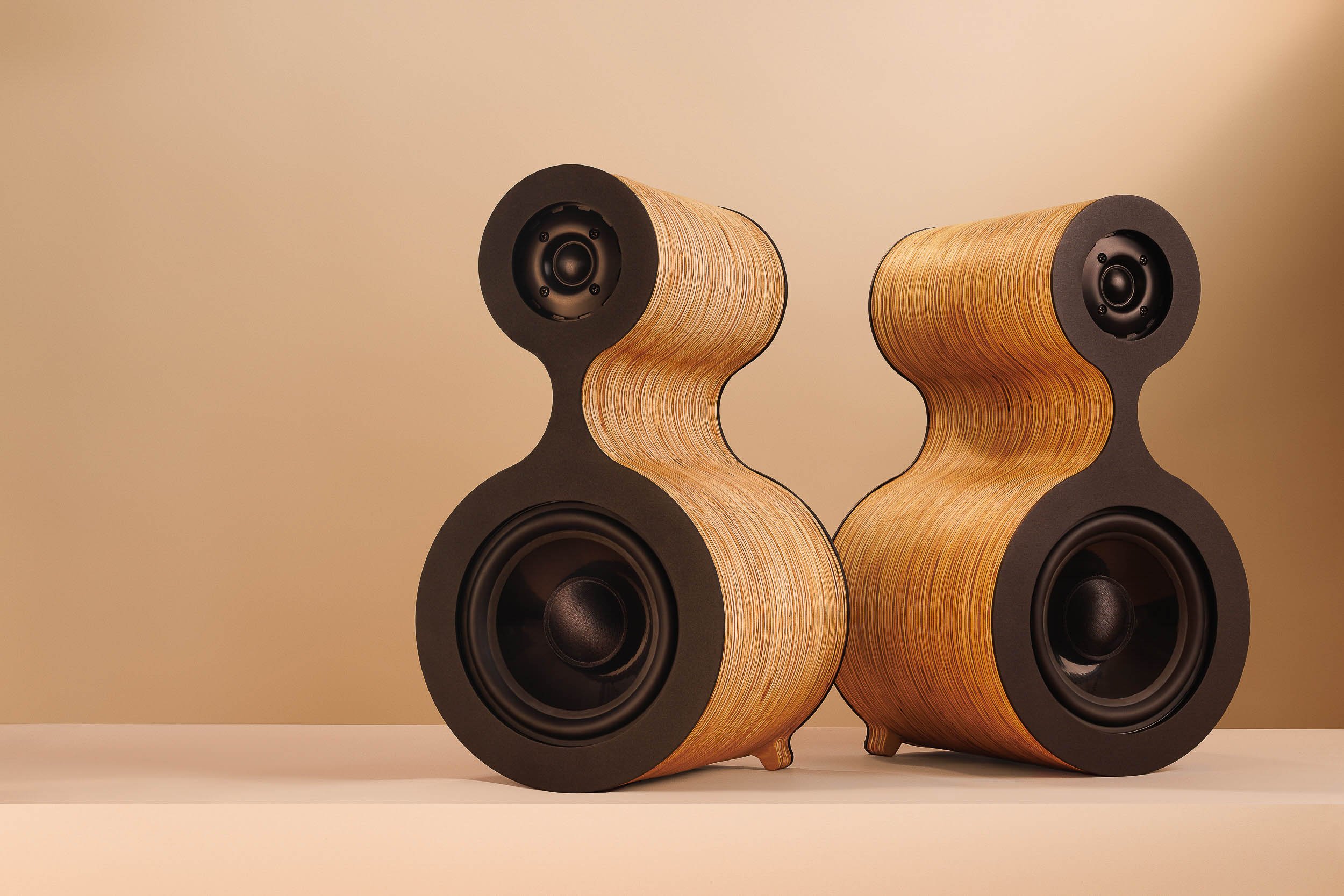 Pair of Fourier Acoustics Calabash speakers facing each other, showing hourglass laminated wood form and black driver baffles
