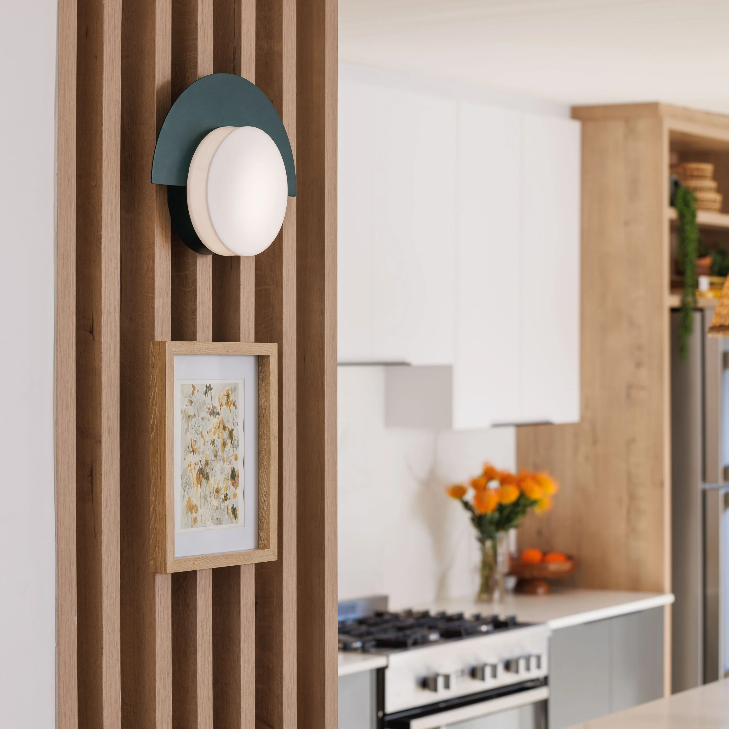 Close-up of a modern wall-mounted light fixture with a navy backing and white curved shade, mounted on wooden slats in a contemporary interior.