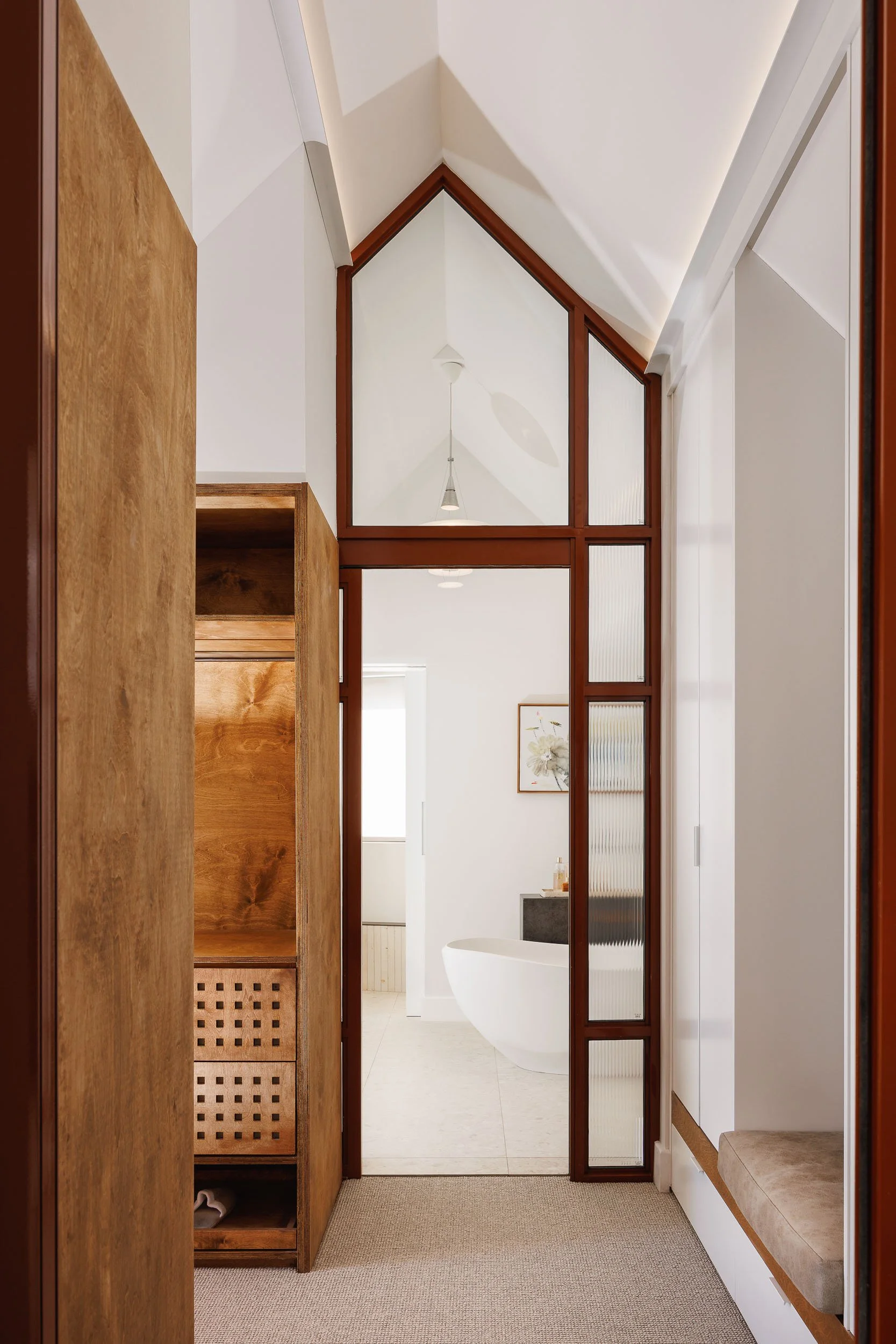 Dressing room corridor with burl timber wardrobe, lattice drawer fronts, and peaked glass partition to ensuite