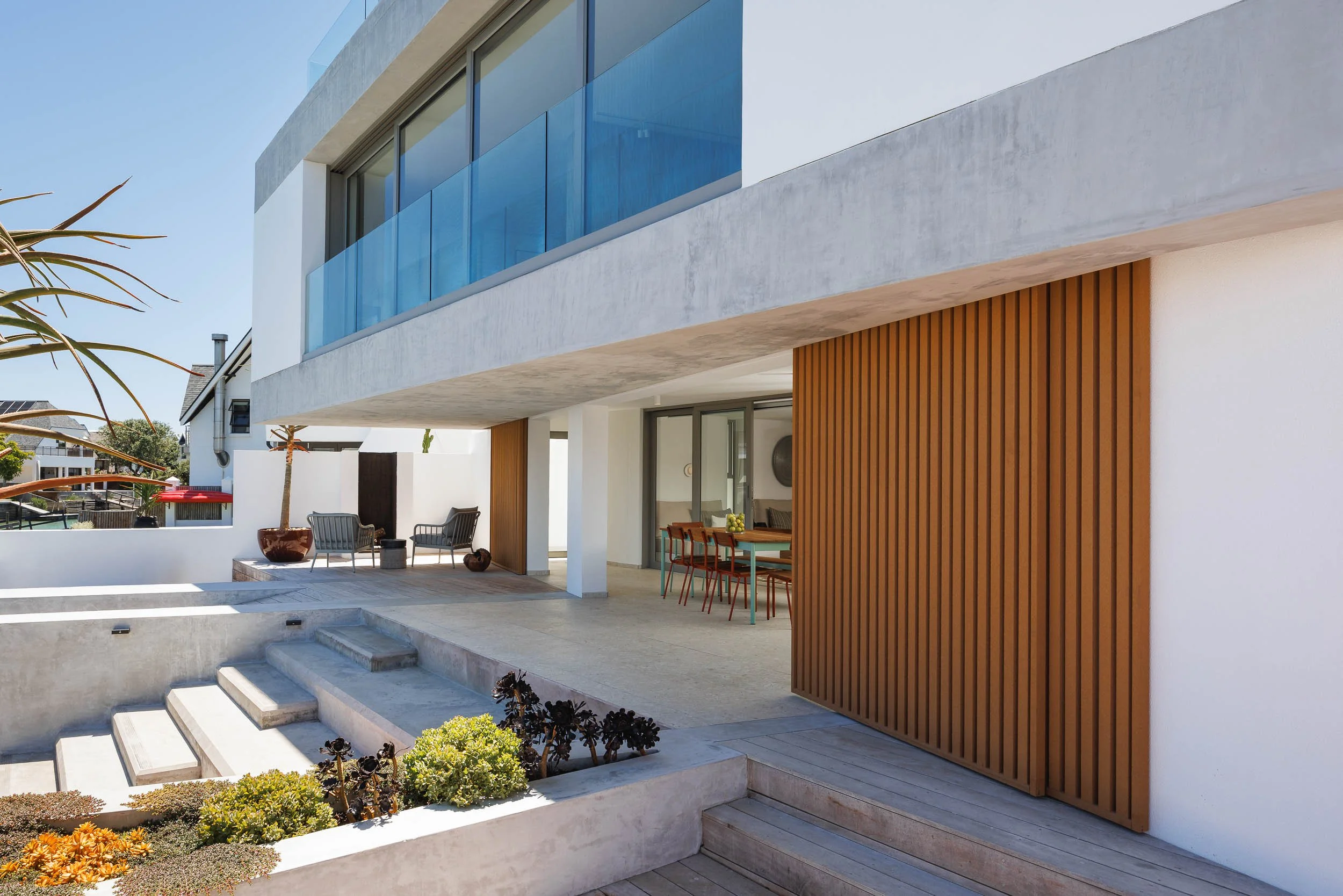 Canal house exterior showing cantilevered concrete slab, timber batten screen, glass balustrades, and planted terraces