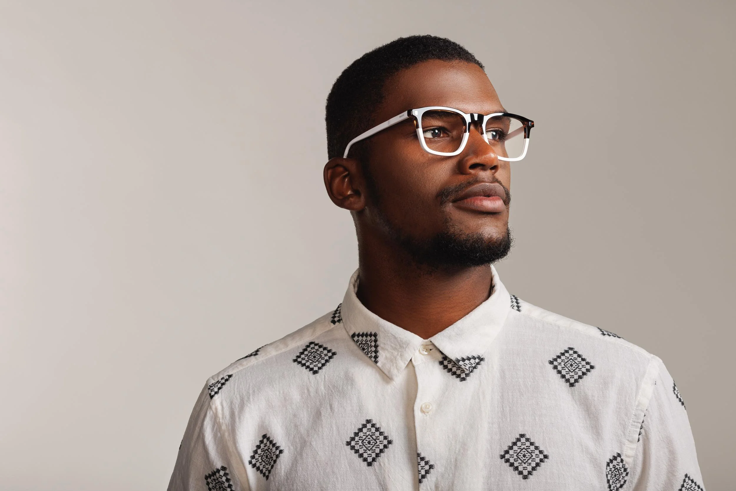 Stylish african man looking into the distance wearing white rimmed glasses