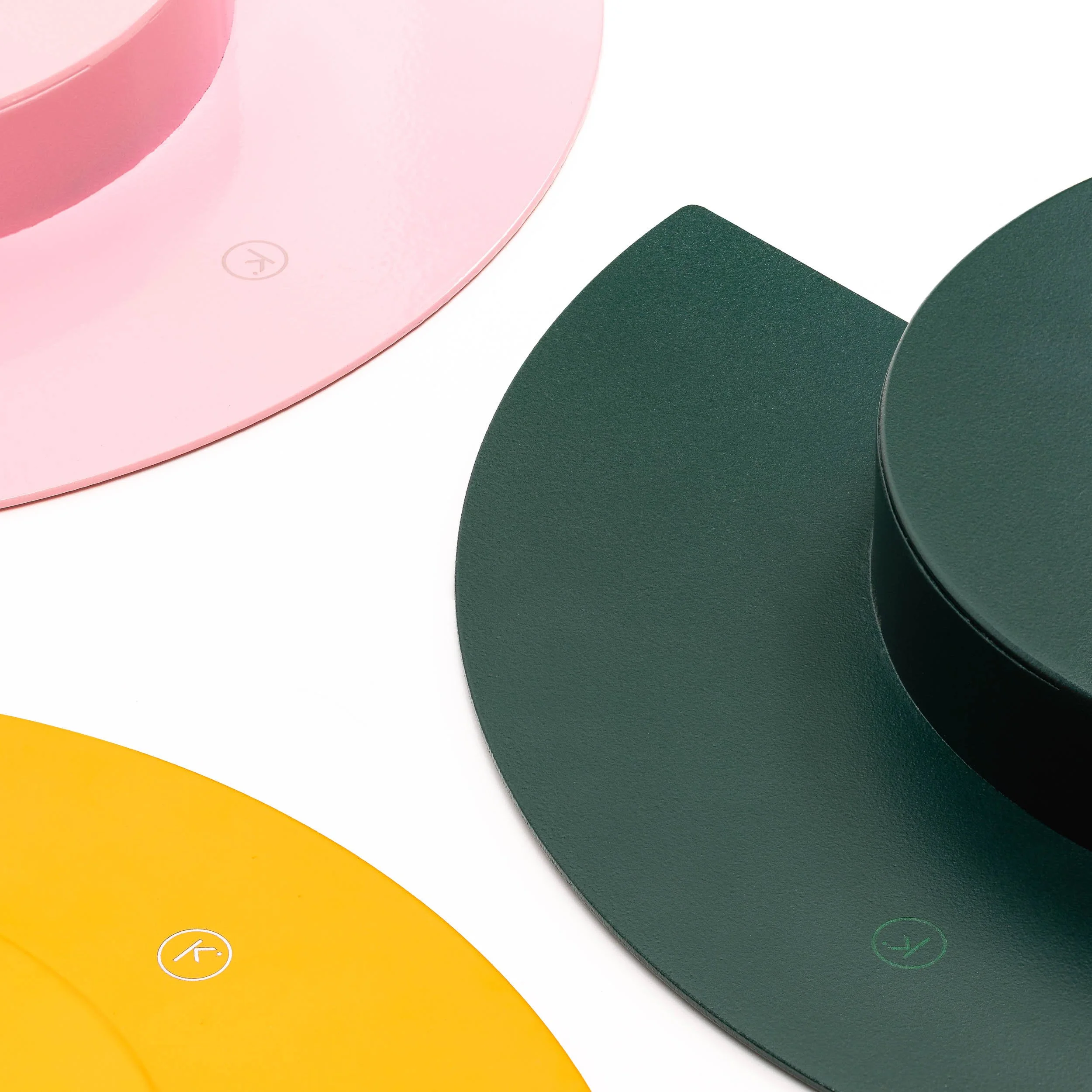 Close-up of three colored yoga mats in pink, green, and yellow with icons for direction, yoga pose, and other symbols printed on each.