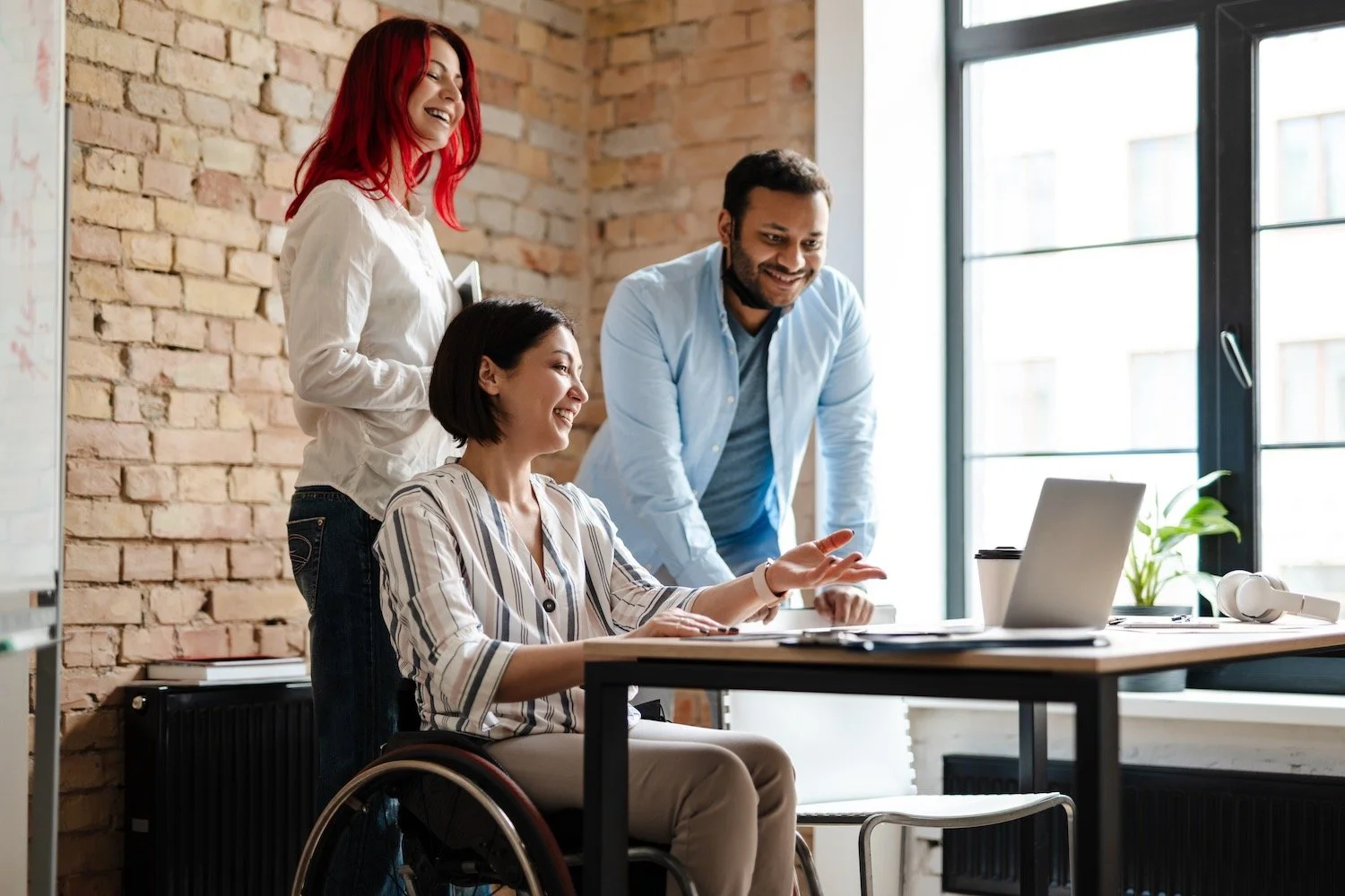 Multiracial smiling three colleagues talking and working with laptop.jpeg