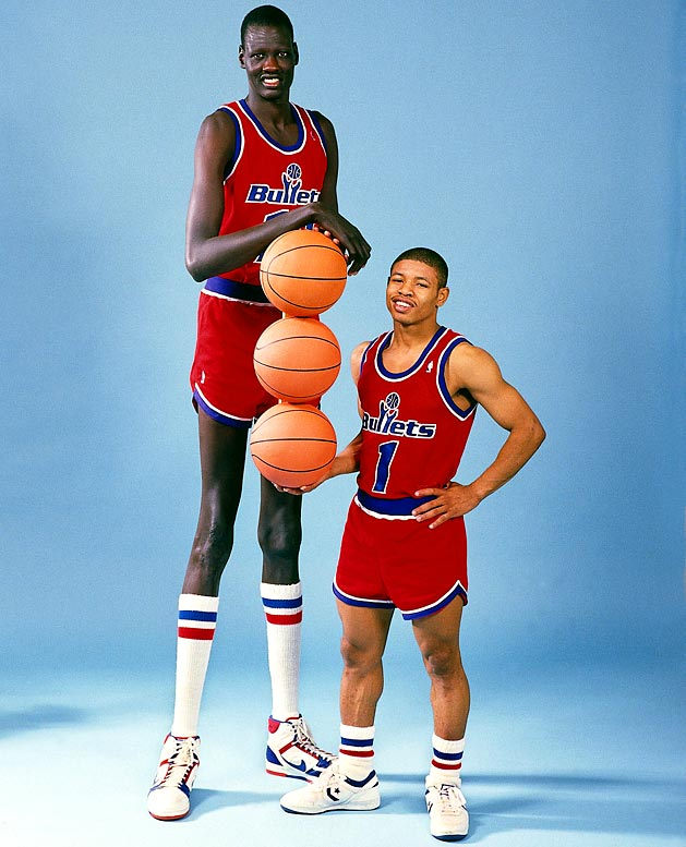 Two Washington Bullets basketball players of drastically different heights pose together holding basketballs.