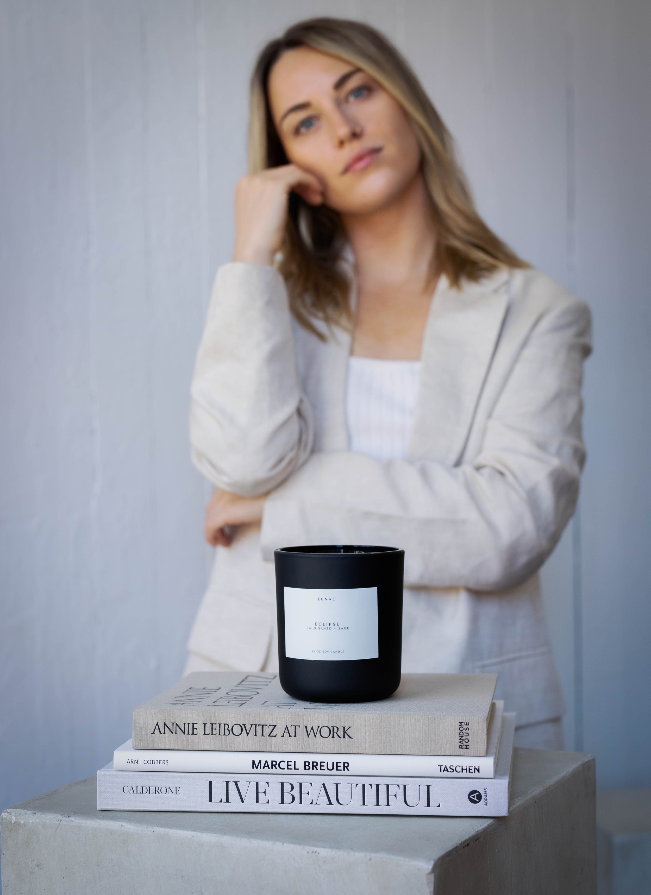portrait of woman standing behind candle and books
