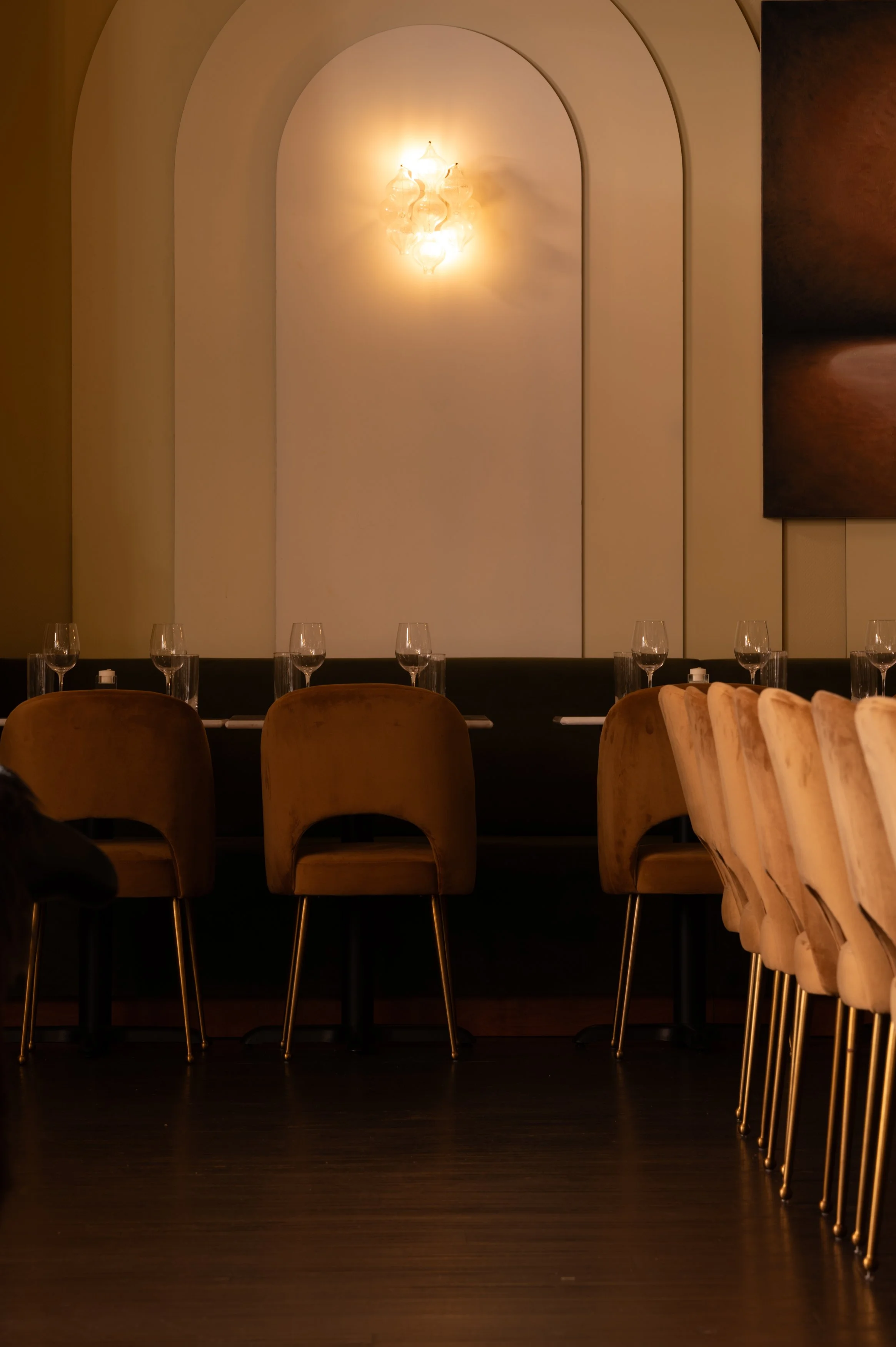 An arched wall alcove and rows of dining chairs in warm evening light