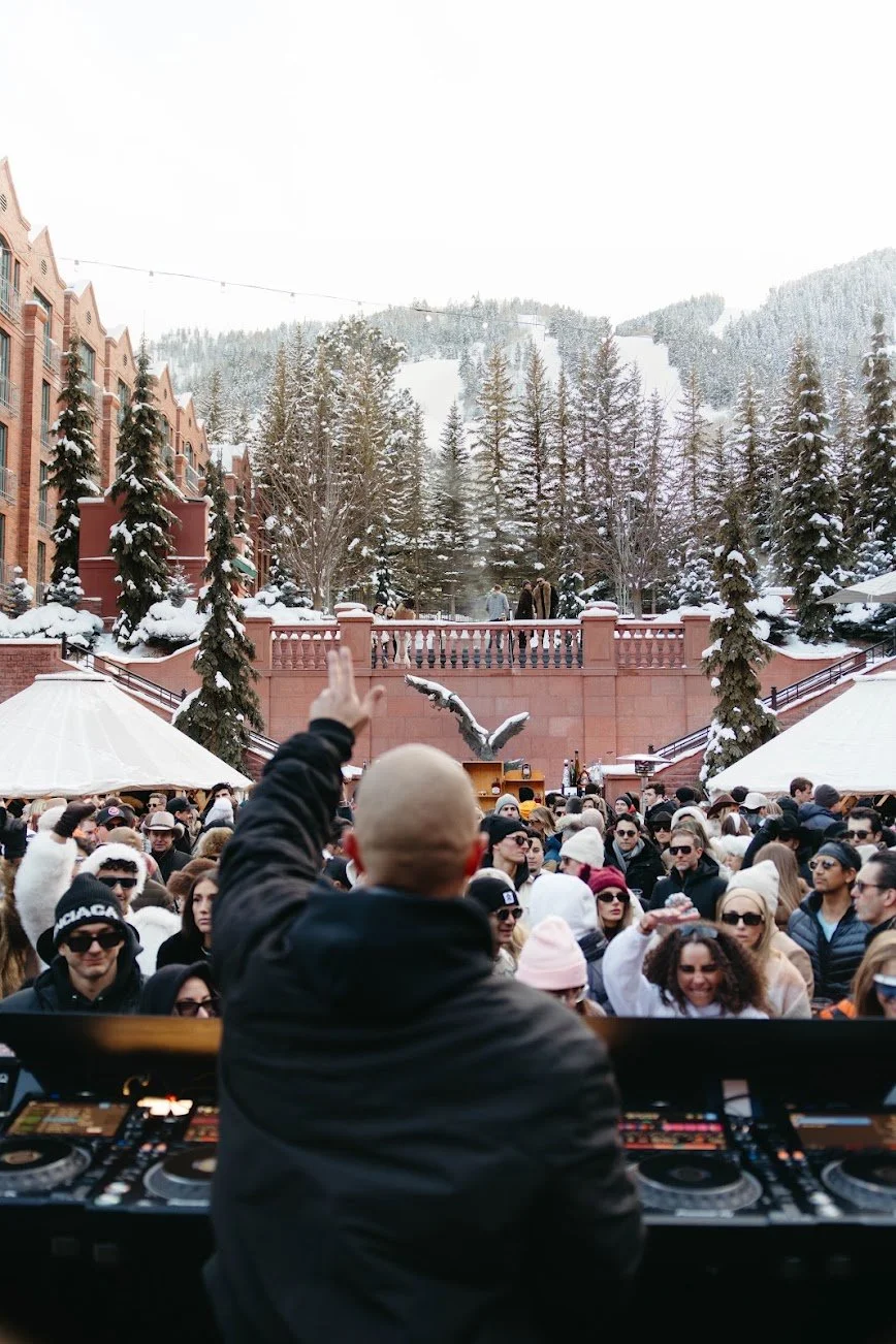 A DJ overlooking the snowy Snow Lodge courtyard and mountain