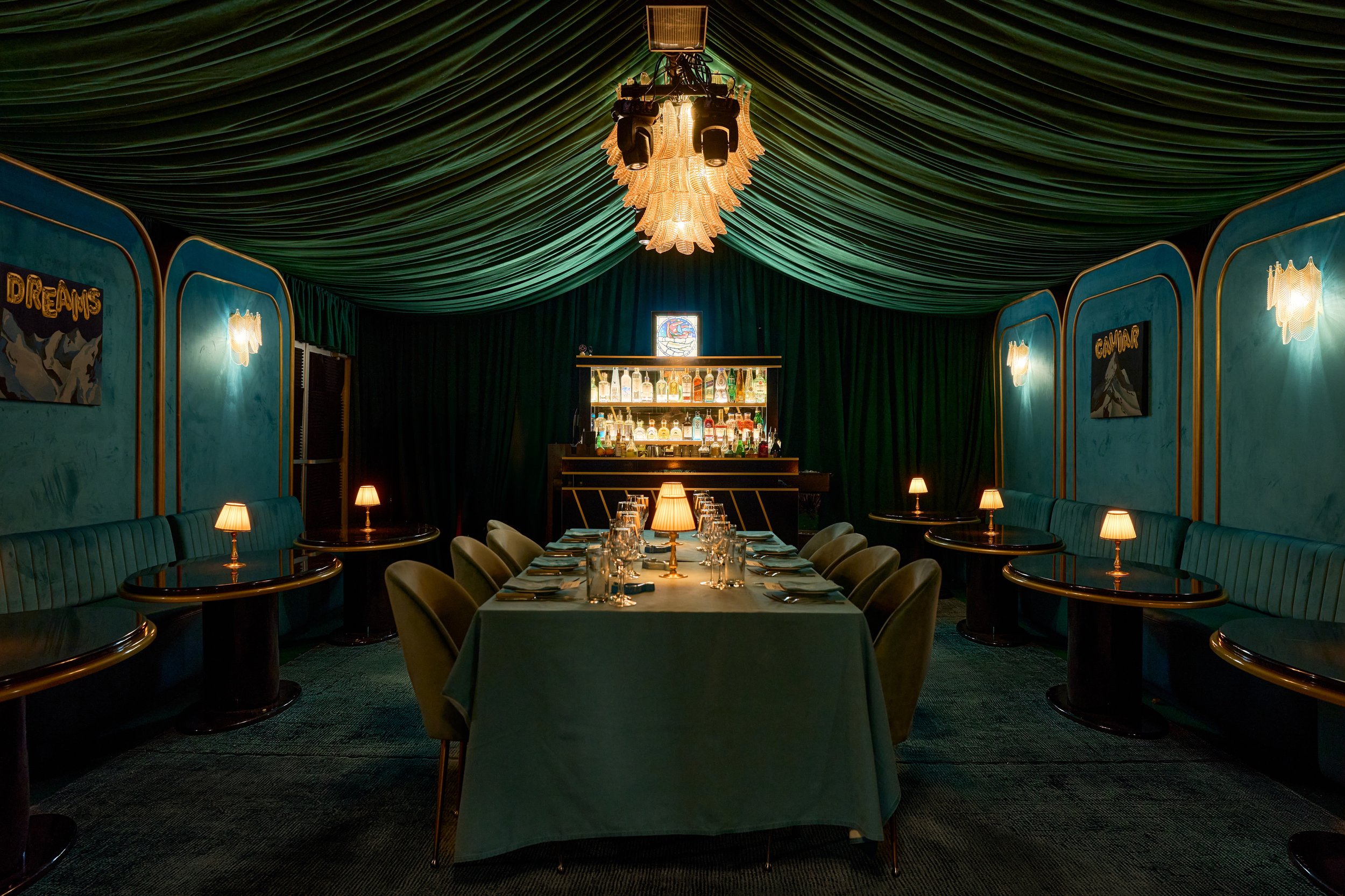 A formal dining table beneath green drapery and a chandelier in The Jade Room