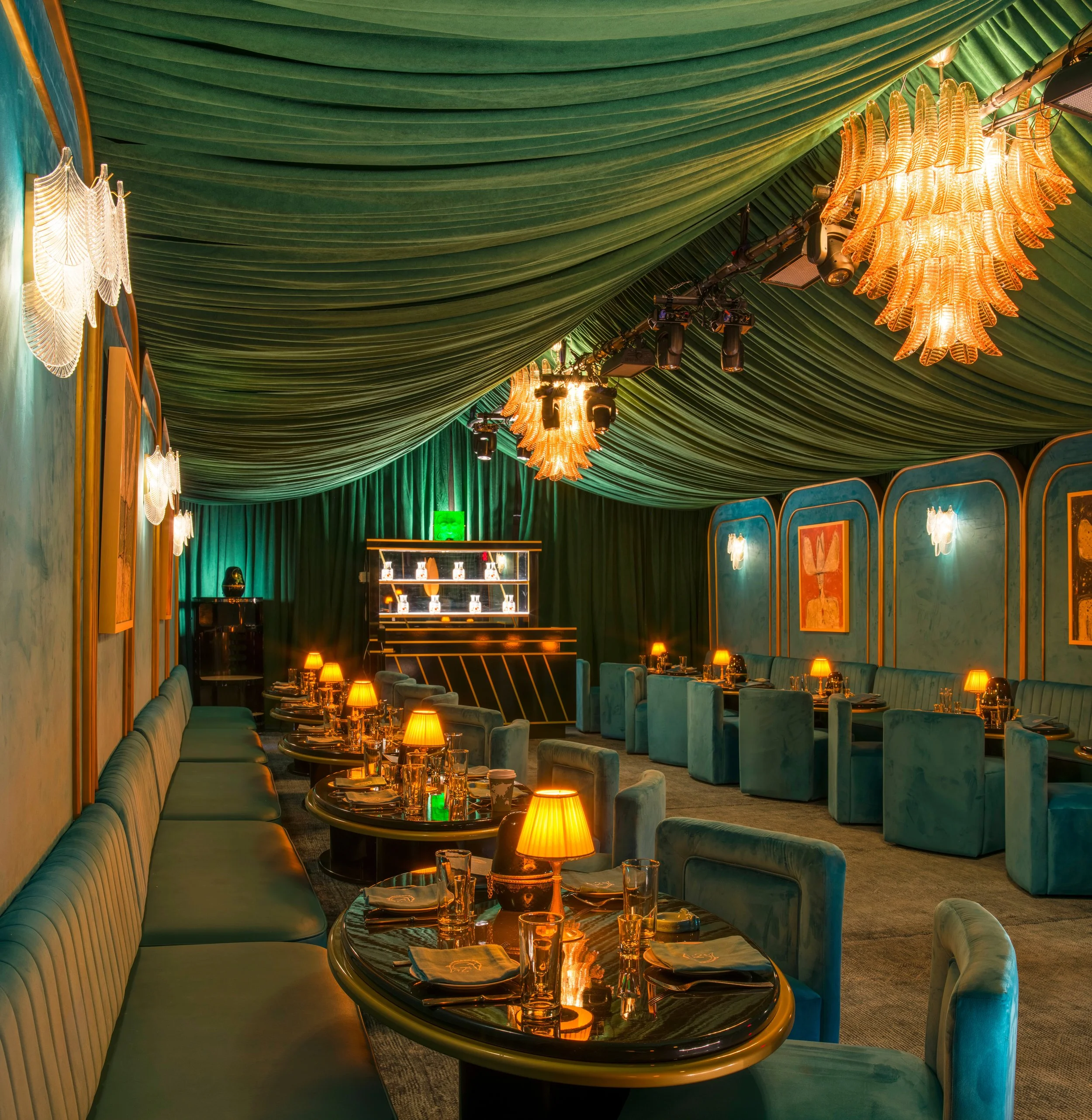 Dining tables beneath emerald drapery and chandeliers inside The Jade Room