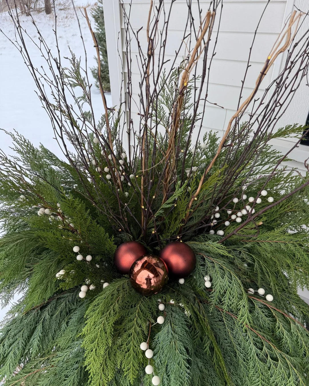 Showstoppers! These pots are all about drama with a mixture of lit and natural branches, beautiful layered cedar greens, white winter berries, and a sophisticated mixture of matte and shine bronze ornaments.