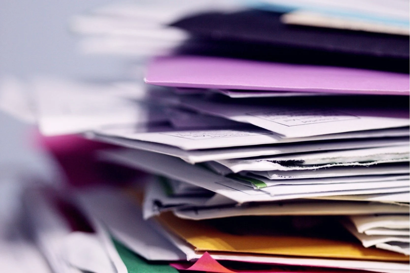a messy stack of papers and folders that need a paper organization system