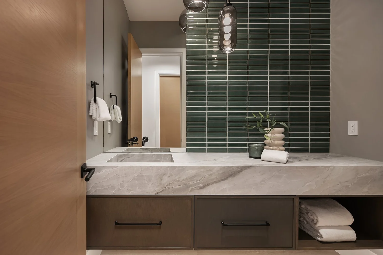Bathroom vanity with green tile, a stone-look countertop, and pendant lighting