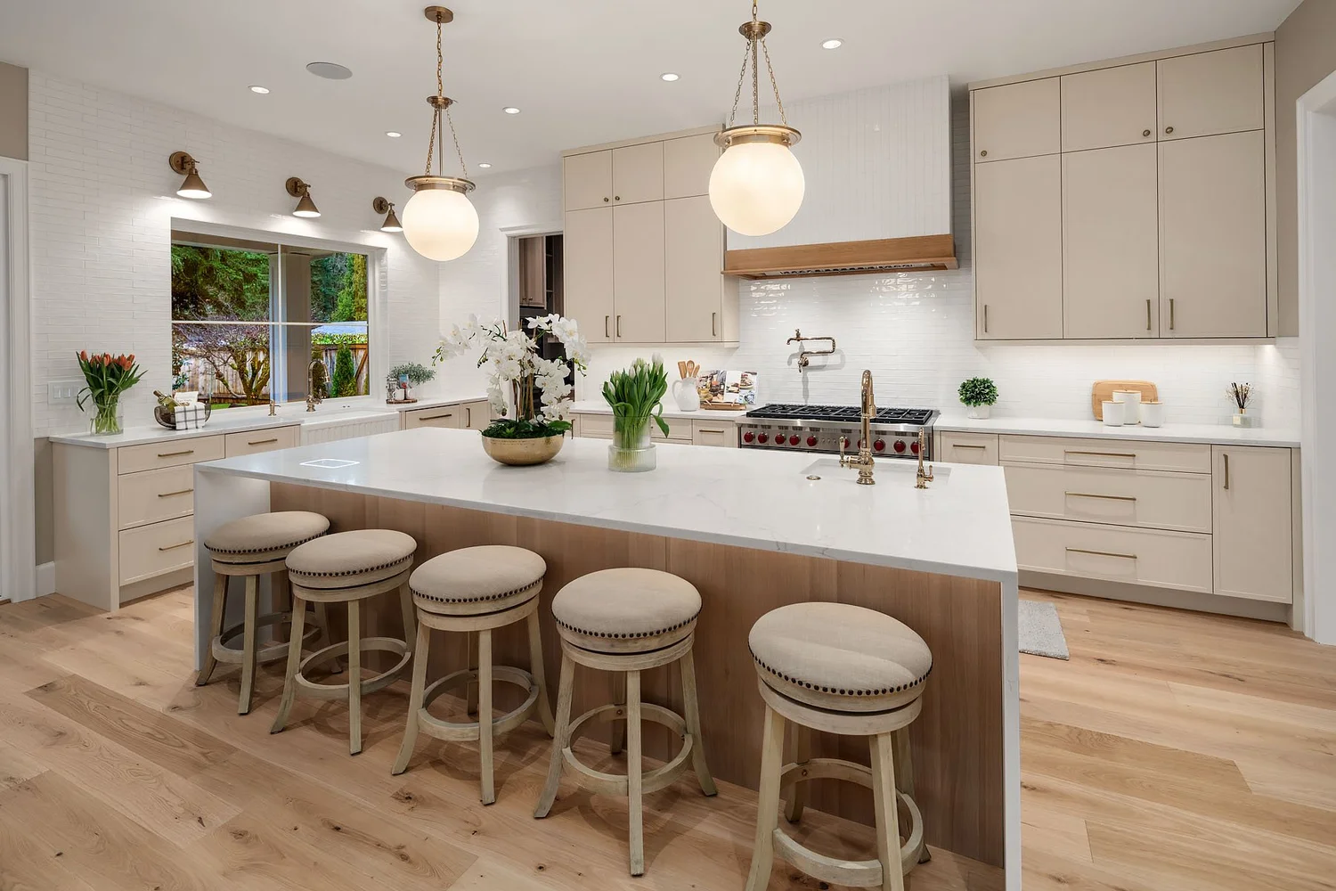 Bright kitchen with globe pendants, a white island, brass-toned fixtures, and warm wood flooring