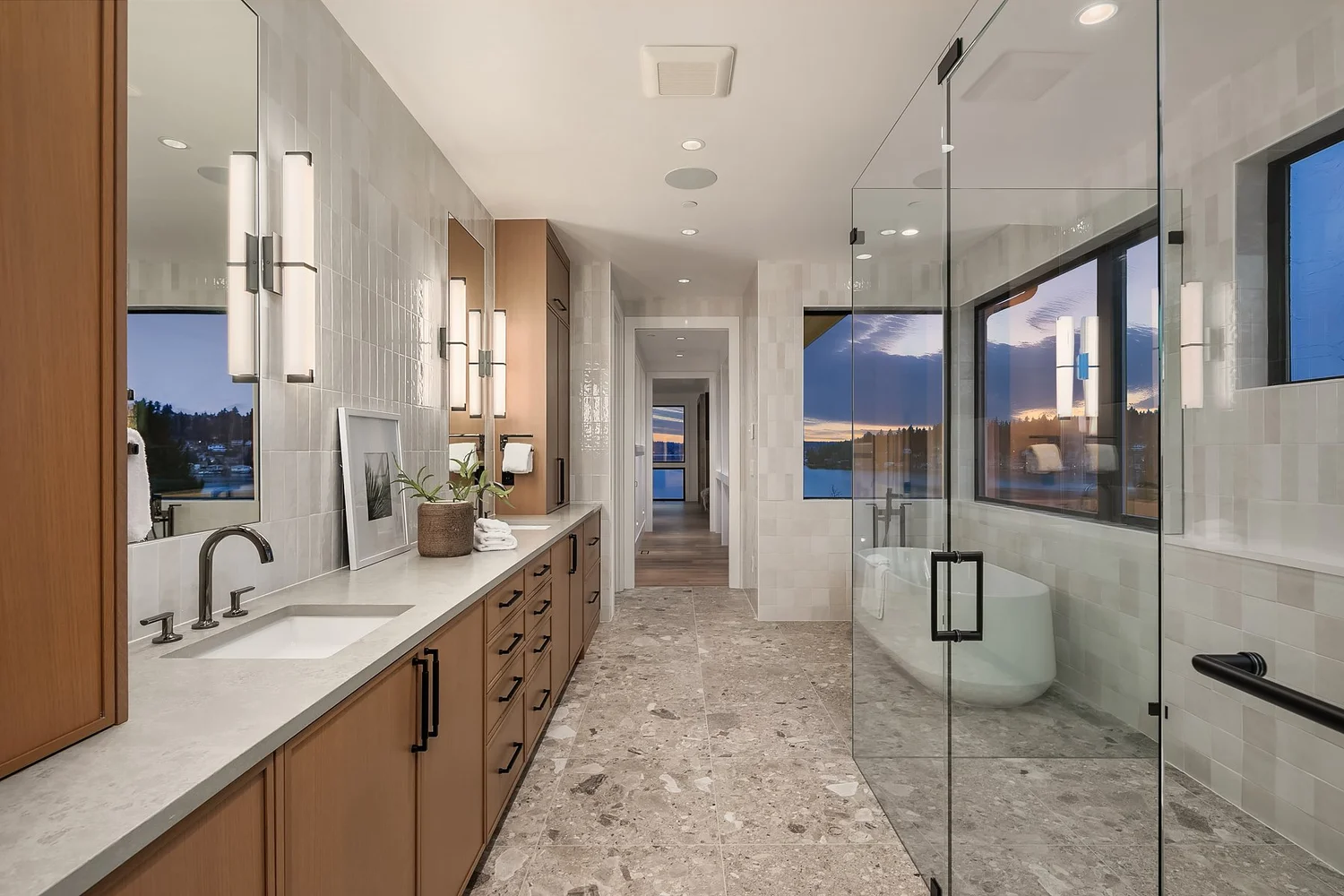 Bathroom with a long vanity and glass shower beside large windows