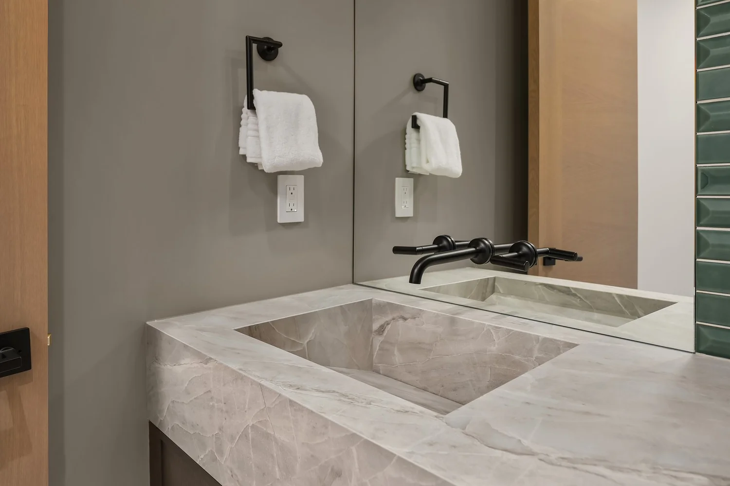 Stone-look bathroom basin with wall-mounted dark faucets