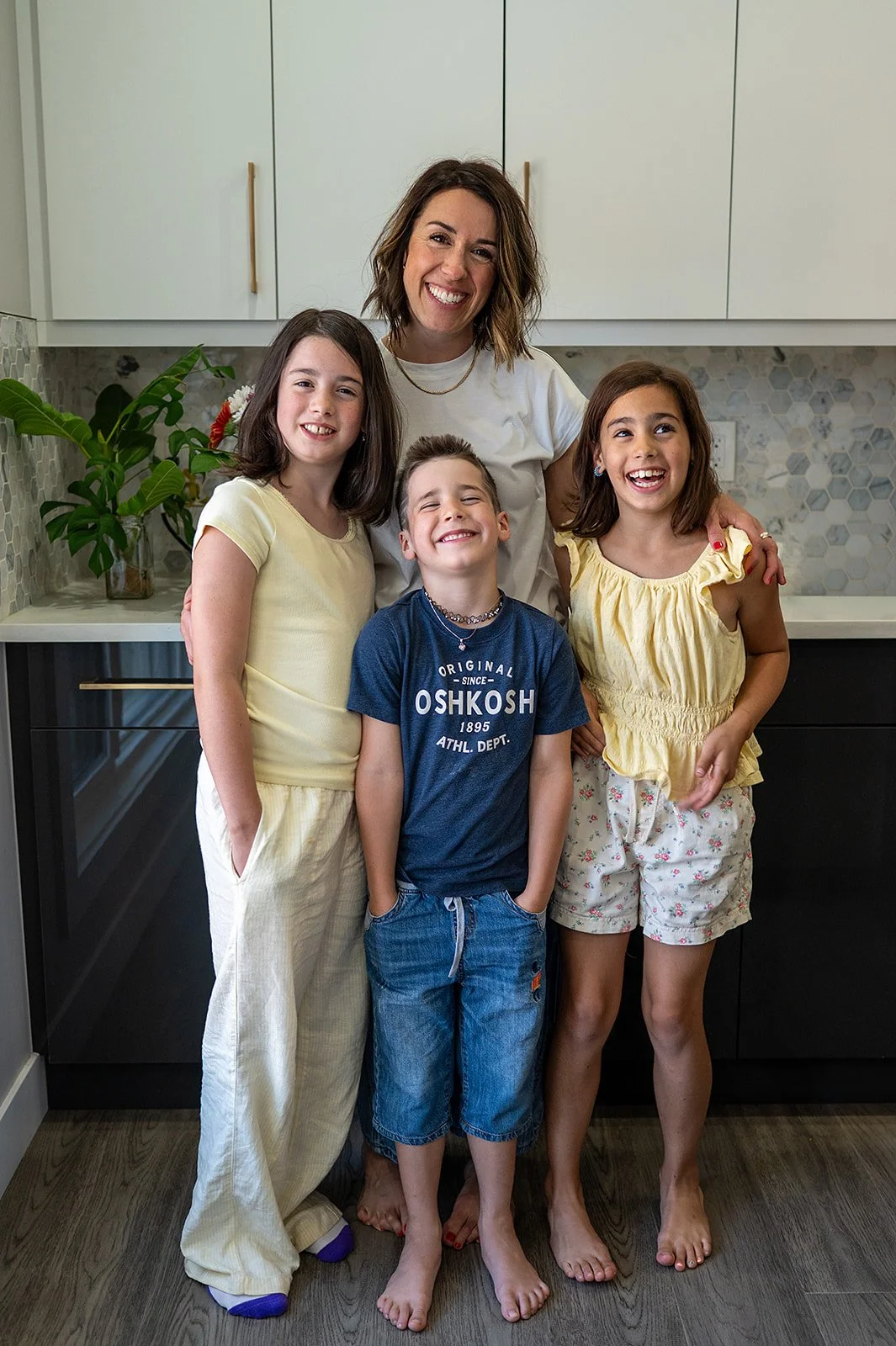 Megan Wallace and her three children laughing together, sharing a joyful moment in the kitchen.