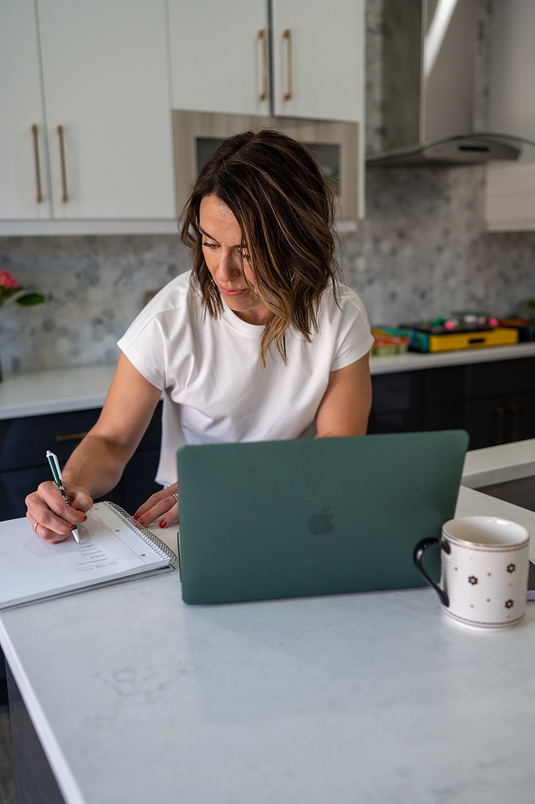 Registered dietitian writing out a personalized meal plan in a notebook at her kitchen island.