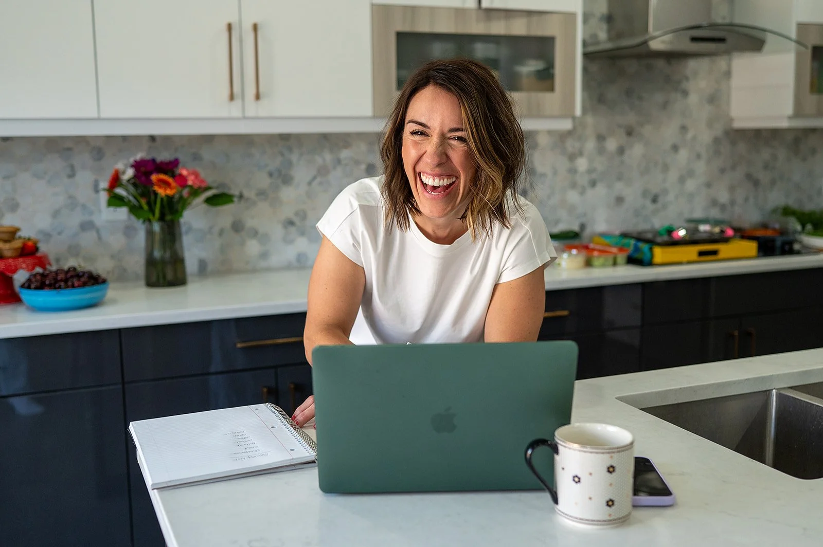 Registered dietitian shares a laugh during a virtual meeting at her kitchen island.