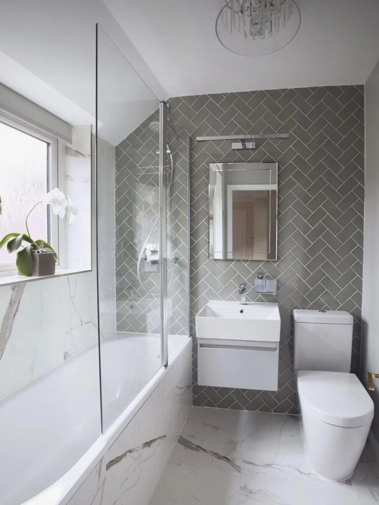 Modern bathroom with a glass-enclosed shower, a white rectangular sink vanity, a wall-mounted mirror, a toilet, a window with a potted orchid, and marble flooring.