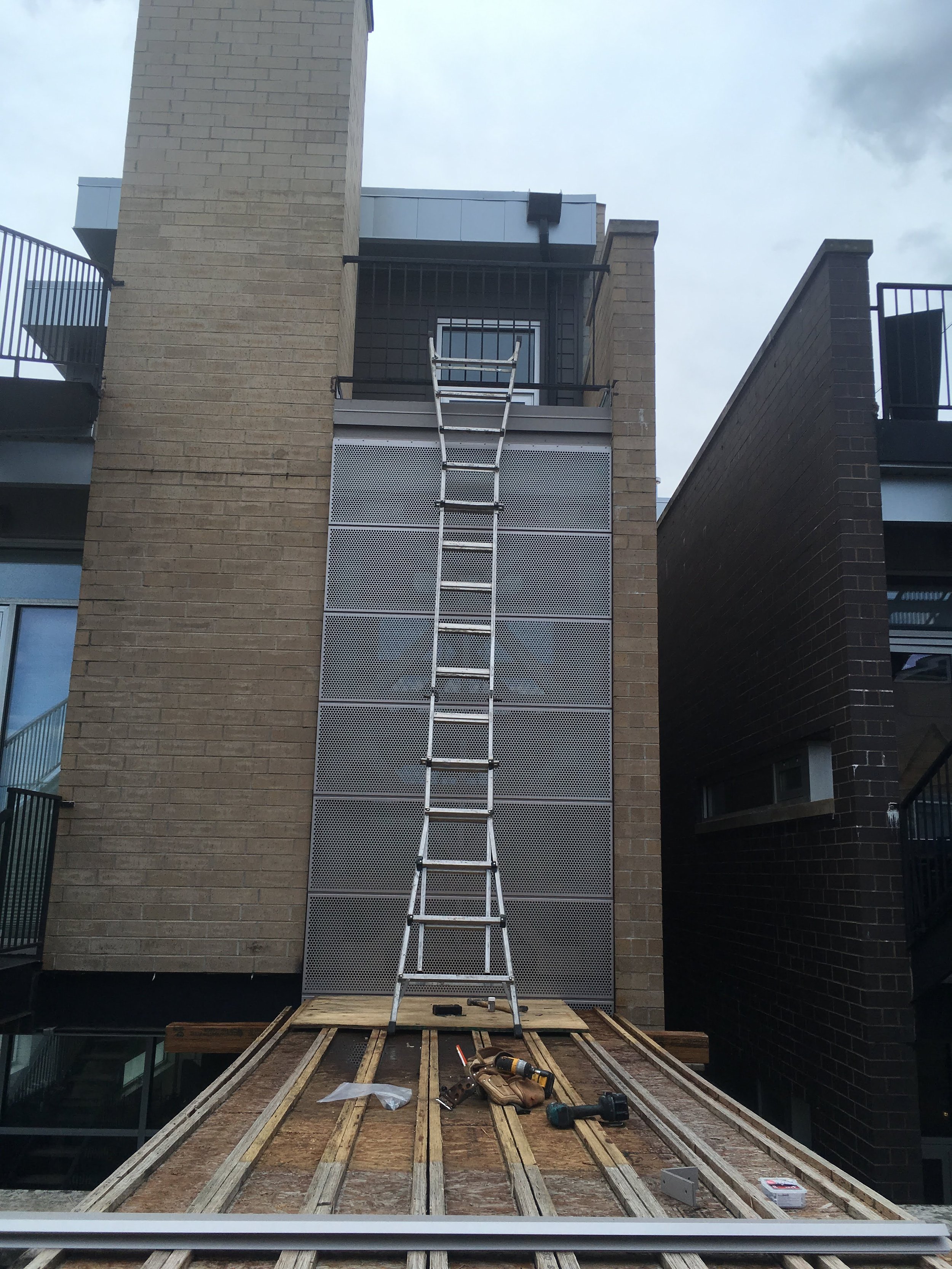 Construction site on a building balcony with scaffolding, tools, and wooden planks laid out for work.