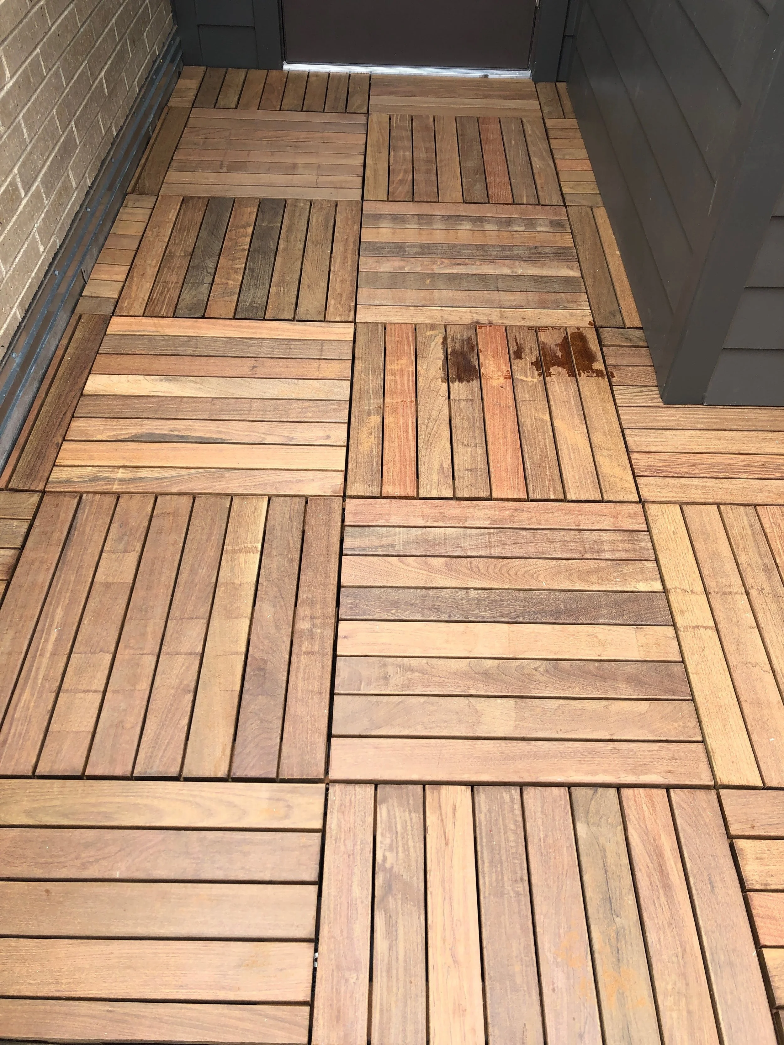 Wooden deck tiles in a grid pattern near a building entrance.