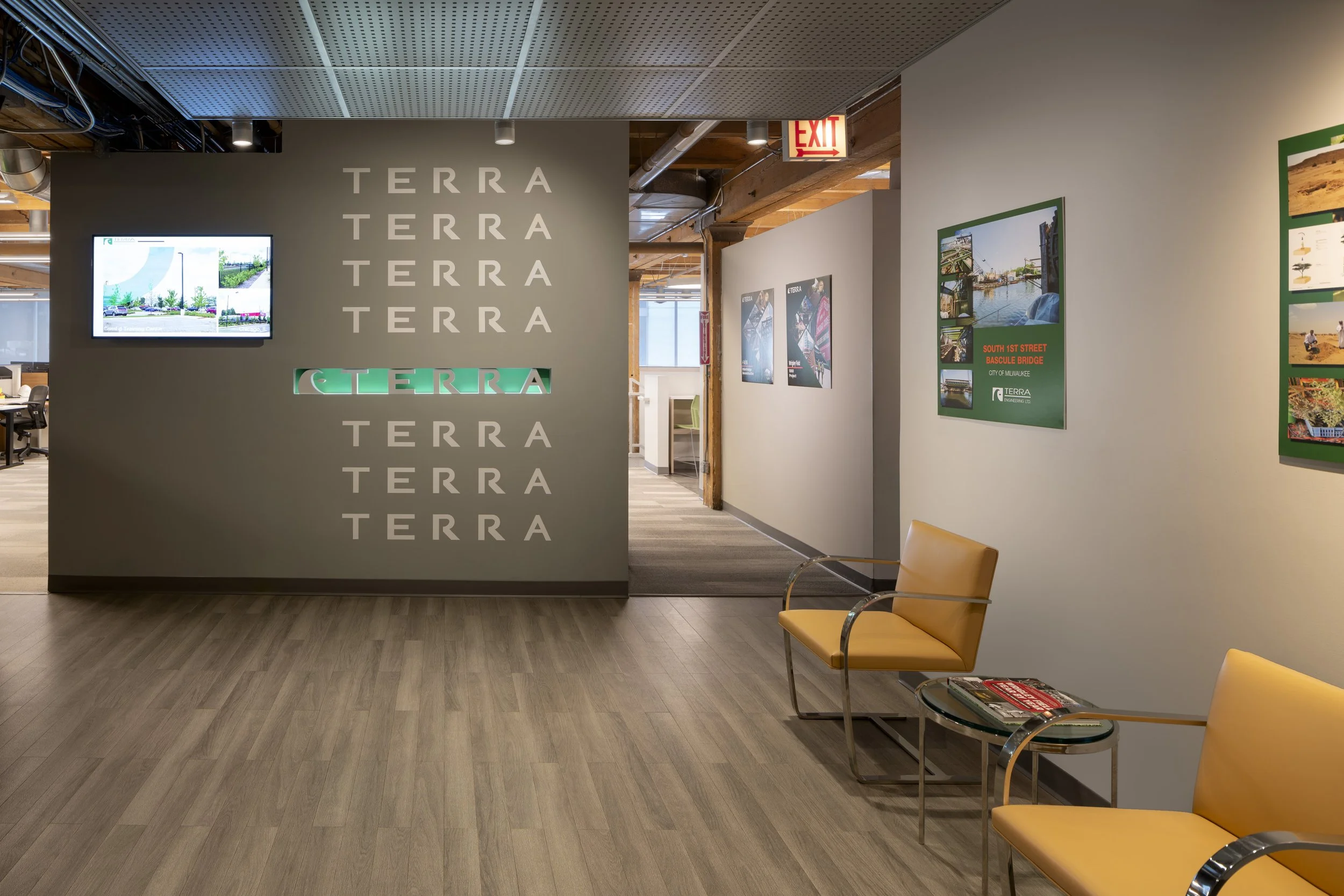 Interior of Terra office with waiting area, yellow chairs, and wall display with 'TERRA' logo and framed photos.
