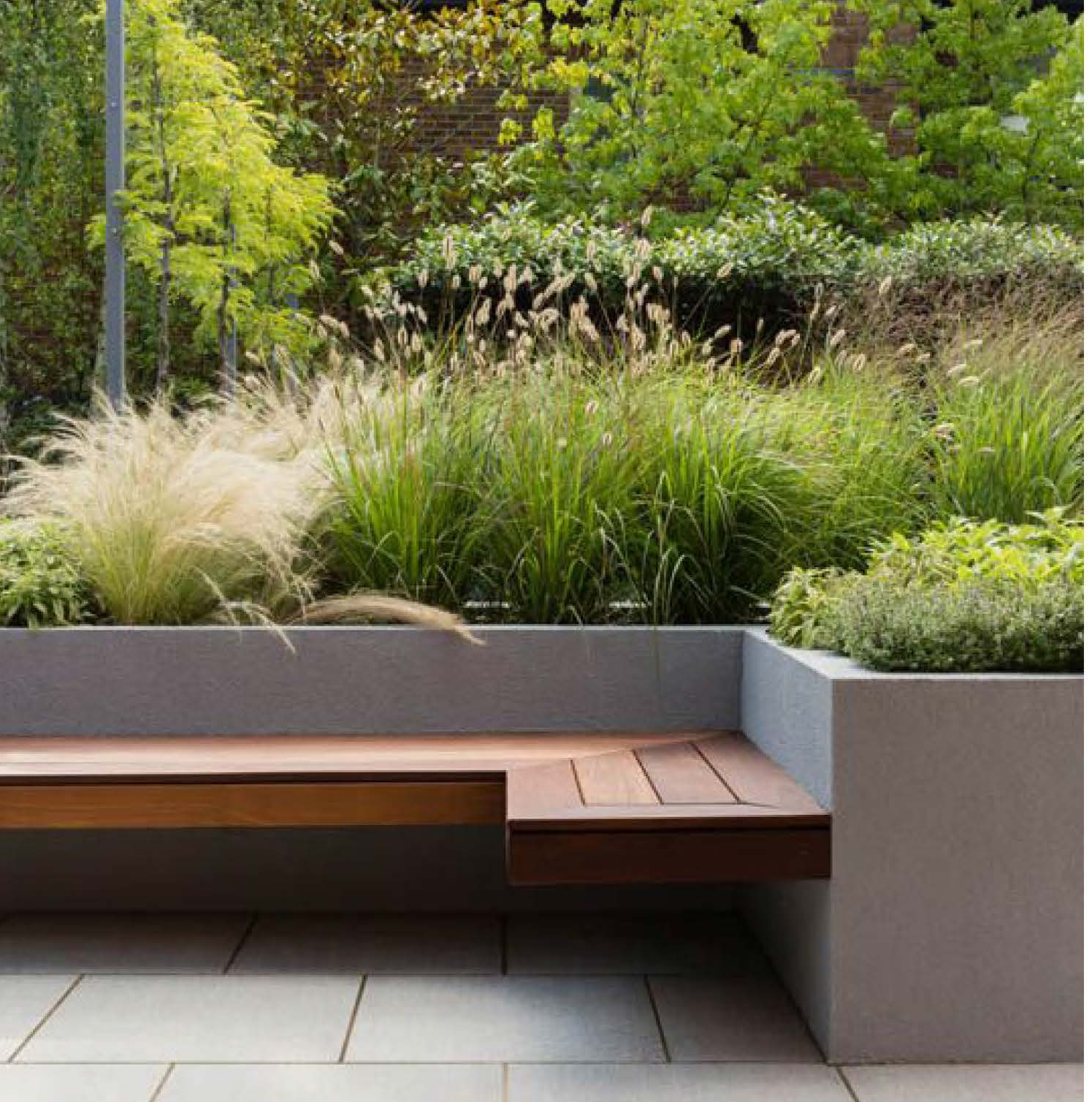 Dog Training Facility. Built-in teak bench set beneath raised concrete planters filled with ornamental grasses, opening onto a light gray paver patio.