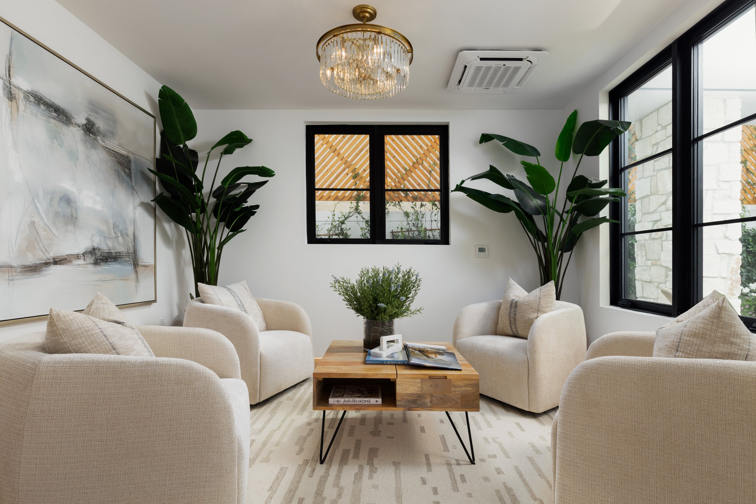 "A serene and symmetrical conversation nook with plush cream seating, lush greenery, and elegant brass accents.