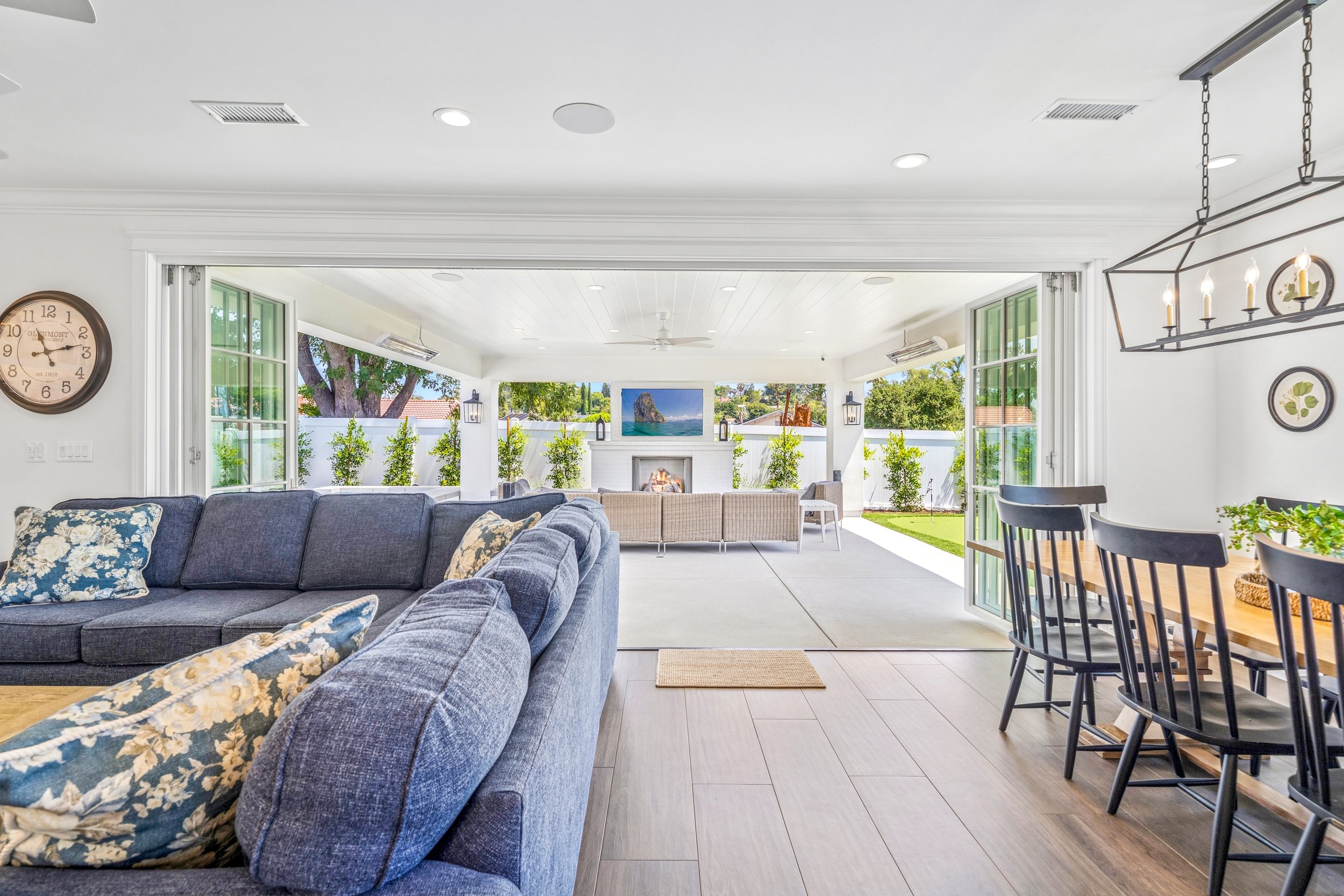 Open concept living room with folding glass doors leading to a covered outdoor lounge, fireplace, and indoor-outdoor entertaining space.