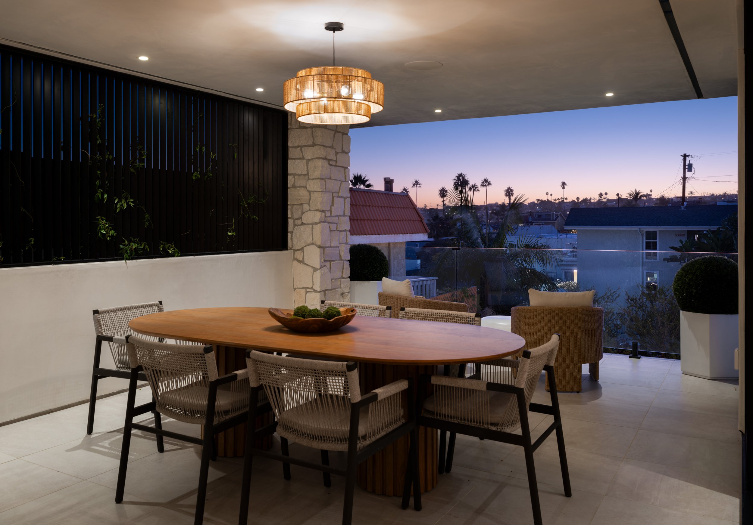 Covered outdoor dining and lounge space with integrated lighting and sunset views, designed for year-round entertaining in Orange County.