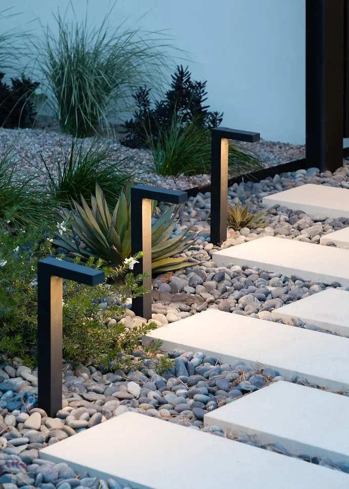 Modern outdoor landscape with pavers, lighting, plants, succulents.
