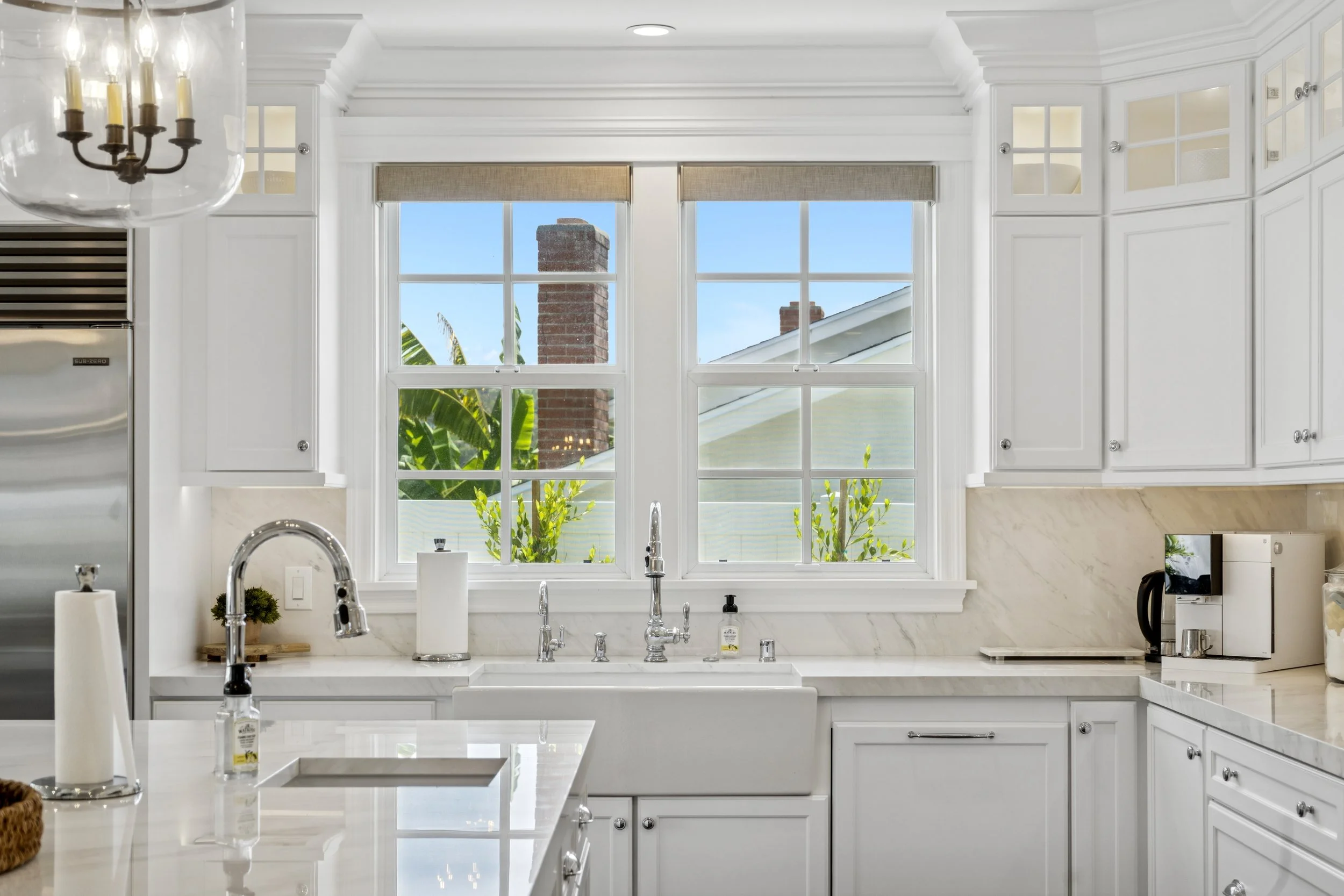 A crisp, all-white dream kitchen with stunning marble accents and plenty of natural light.