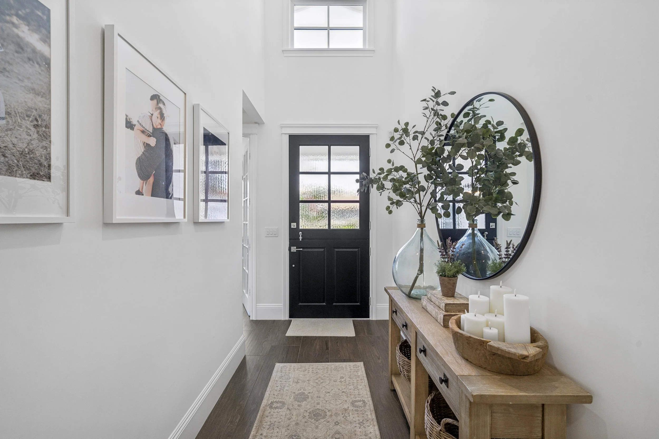 A chic and airy entryway featuring neutral textures, a statement black door, and a perfectly styled console.
