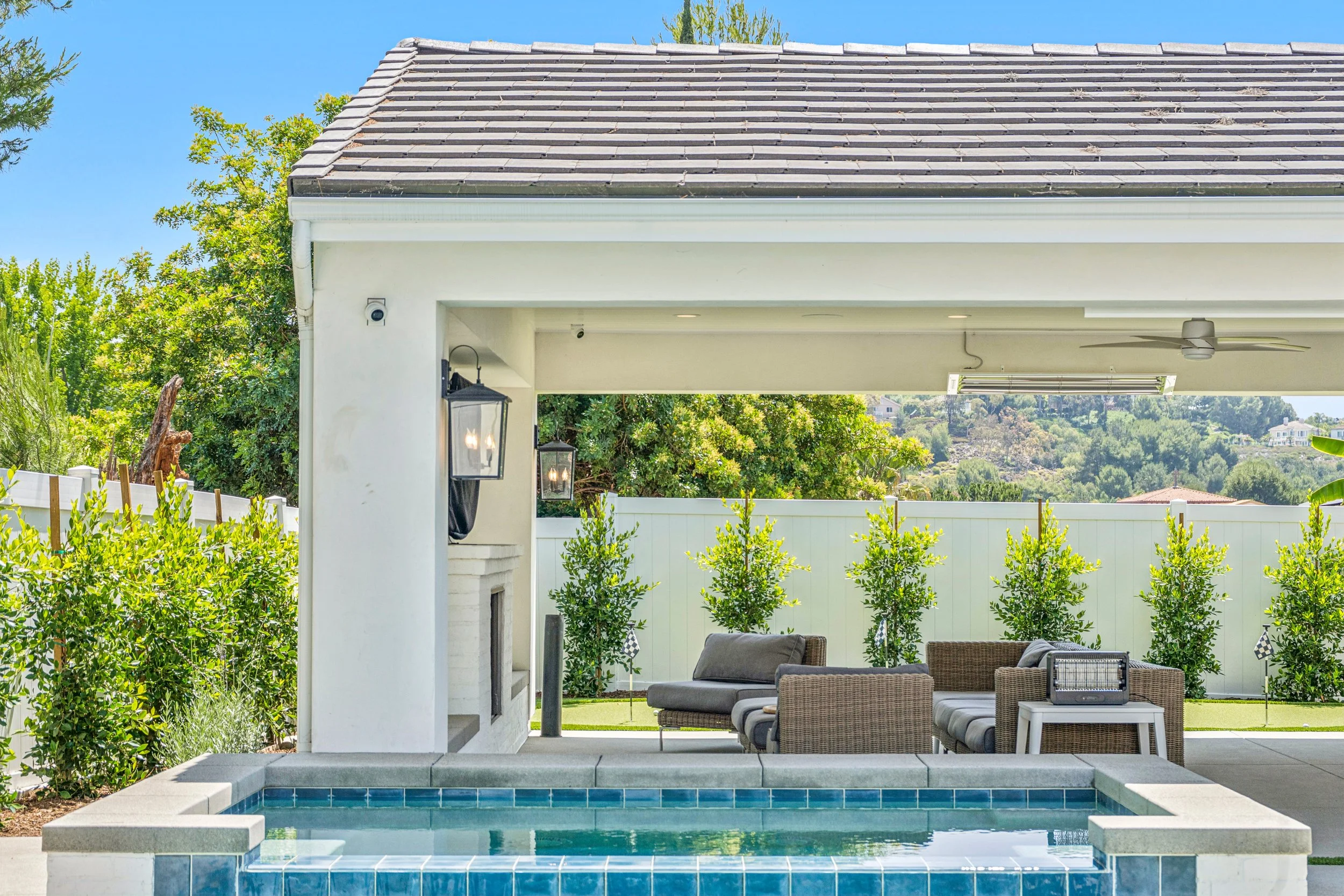 The perfect outdoor retreat featuring a sleek pool, spa, and a cozy shaded lounge.