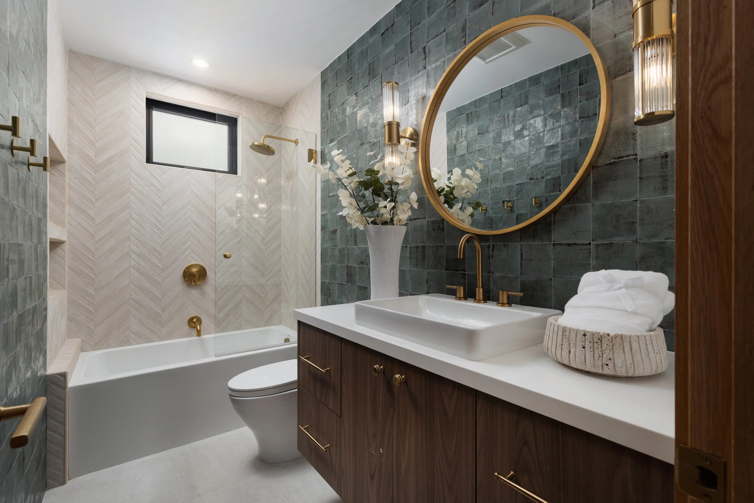 Orange County bathroom remodel featuring blue handmade-look tile, a custom wood vanity, brass fixtures, and a glass-enclosed tub and shower.